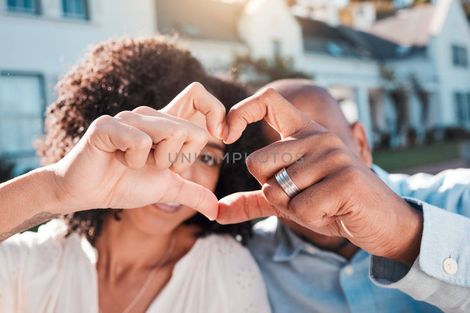 Love, couple and heart hands outside of new house, property or real estate success. Emoji, shape and woman with man in front of dream home in celebration of rental, moving or homeowner milestone by YuriArcurs