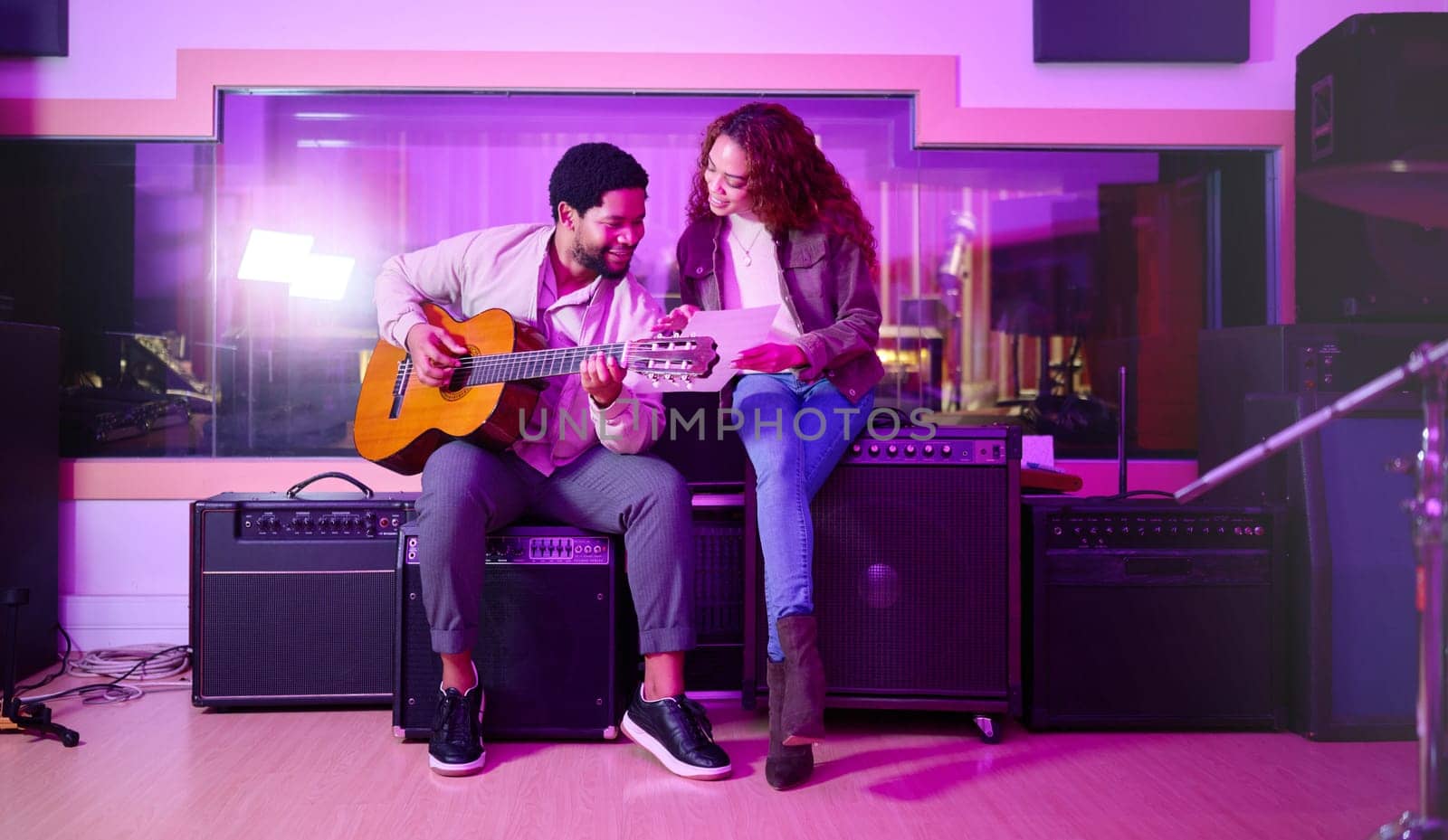 Black man, woman and songwriting with guitar, studio and night with paper for creative lyrics, notes and ideas. Music team, writing and singing together for professional production with teamwork.