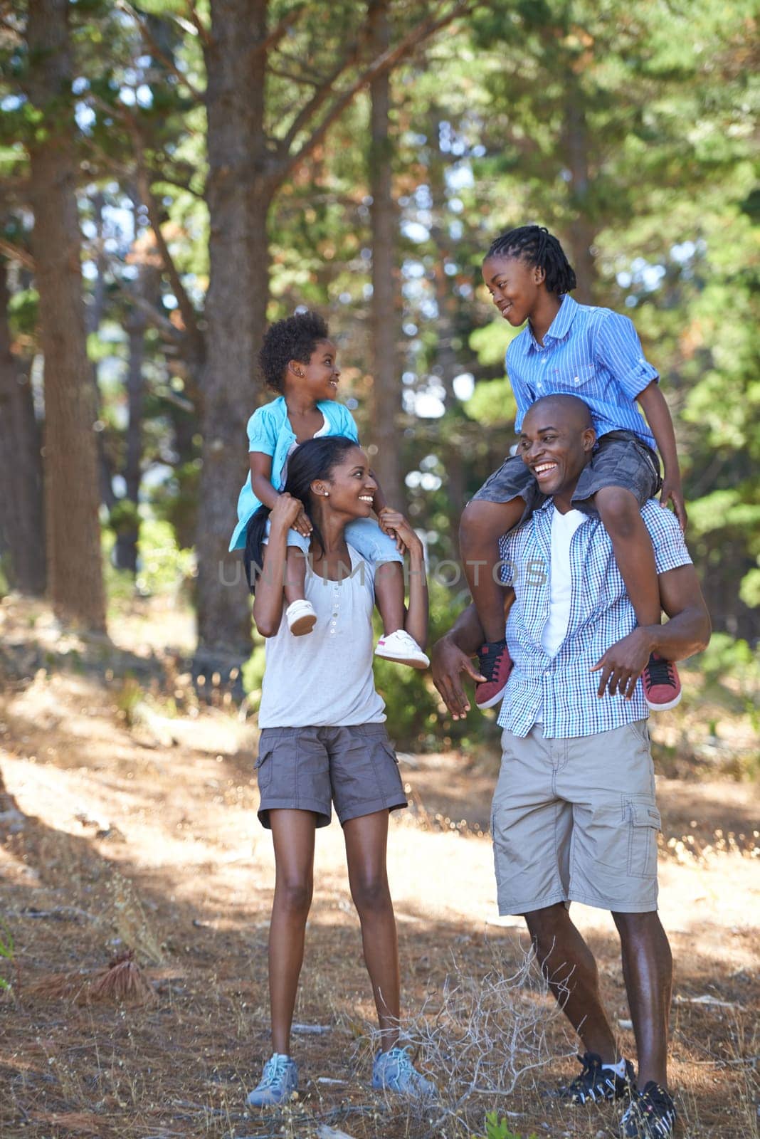 Giving the kids a break from the hike. Portrait of a mother and father carrying their children on their shoulders while out for a hike