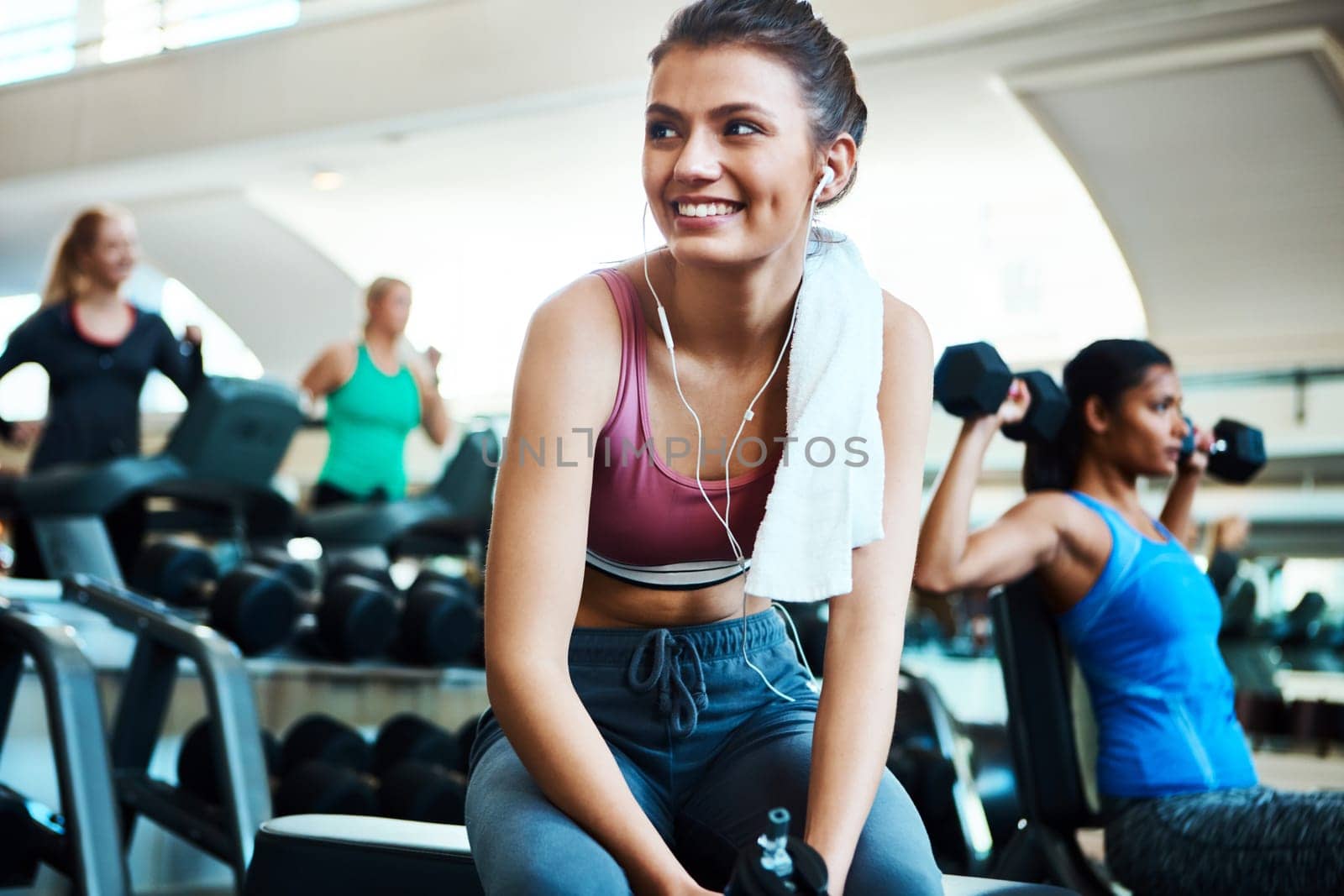 Now shes ready for a workout. an attractive young woman taking a break from her workout in the gym. by YuriArcurs