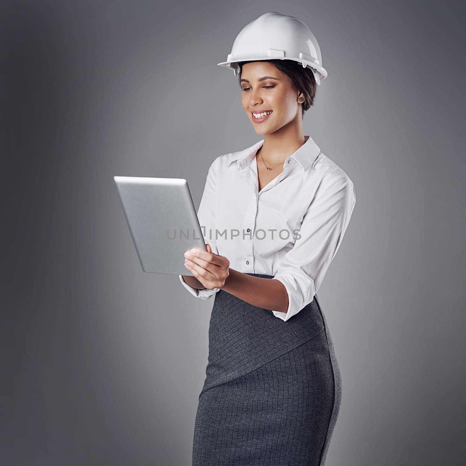 This progress report is looking great. a well-dressed civil engineer using her tablet while standing in the studio. by YuriArcurs