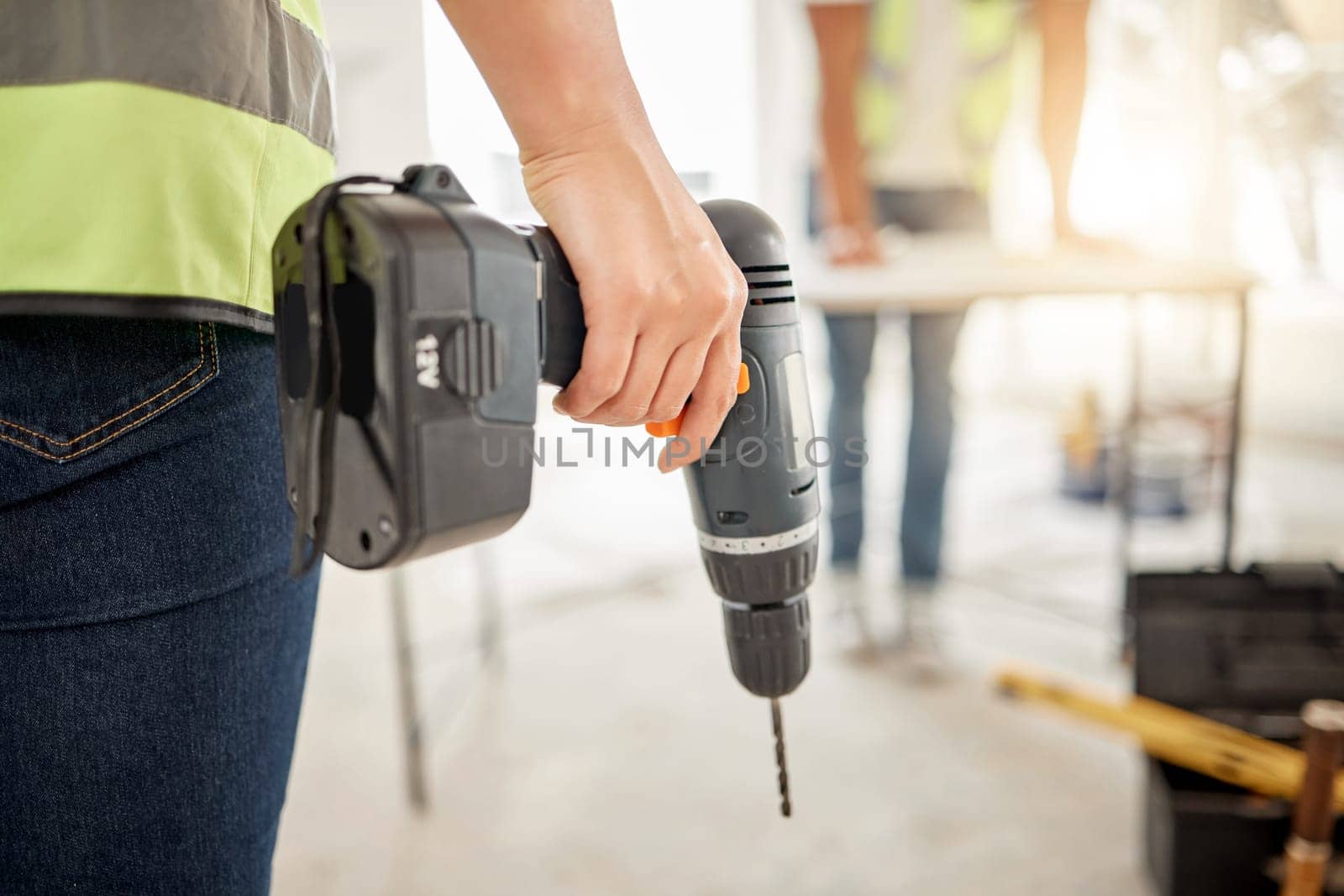 Drill, construction and hand of handyman for home renovation, maintenance or carpenter work. Back of engineer, constructor or contractor person with electric power tools in room or building site.