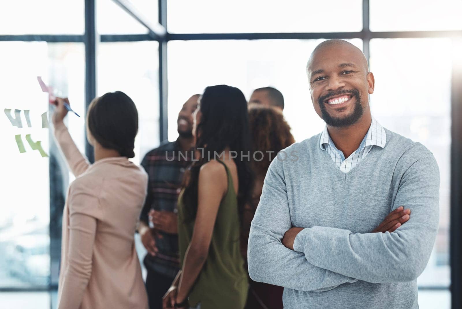 Proud to be the leader of such a great team. Portrait of a handsome mature man standing in the office with his colleagues in the background