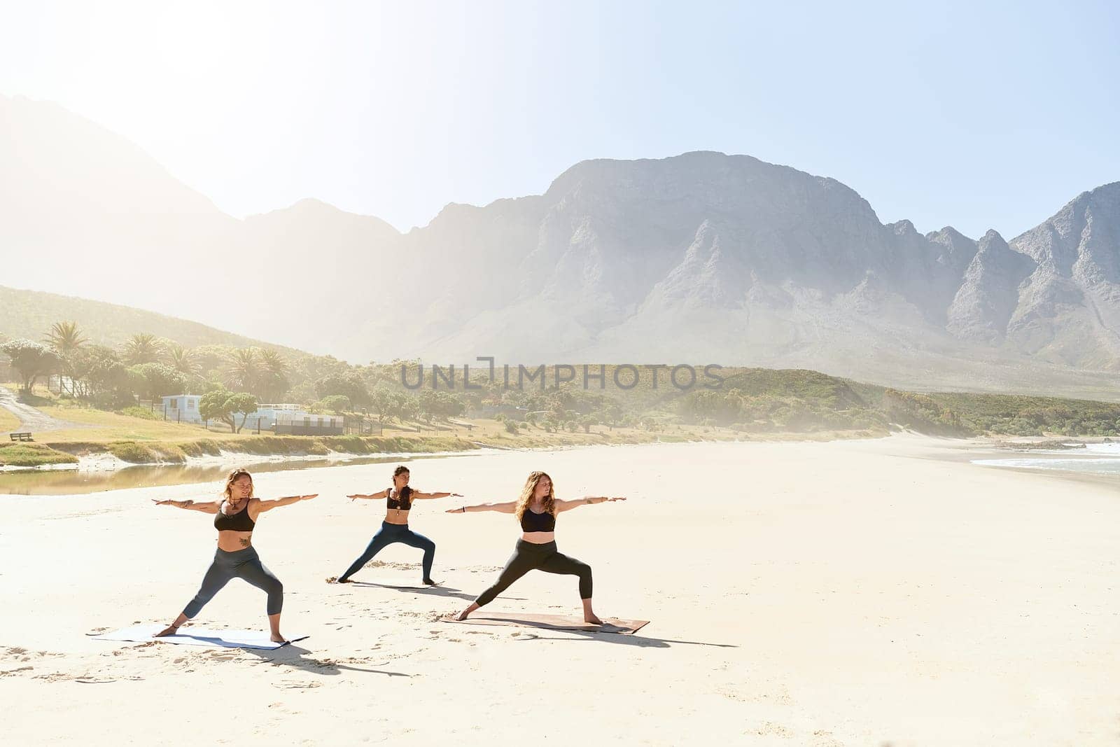 Yoga is an art which connects our soul, mind and body. three young women practicing yoga on the beach. by YuriArcurs