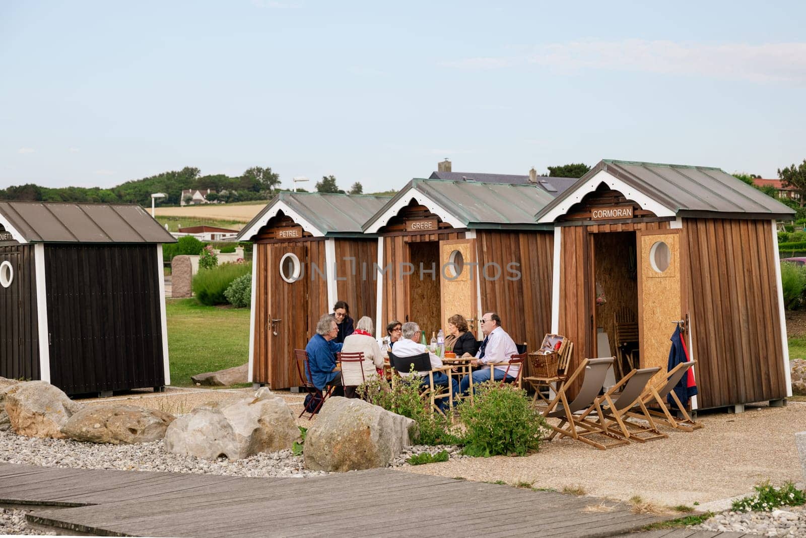 SAINTE-MARGUERITE-SUR-MER, FRANCE - JULY 01, 2018: People at a picnic near their wooden houses or bathing cabins on the Atlantic ocean