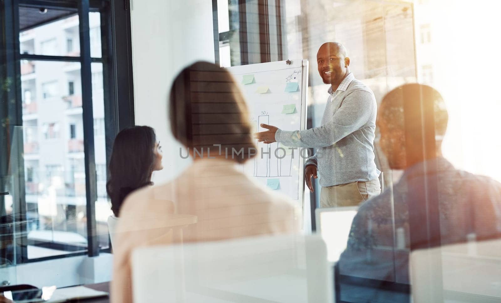 Communicating a bold, specific, and consistent vision. A businessman giving a presentation to coworkers in the boardroom. by YuriArcurs