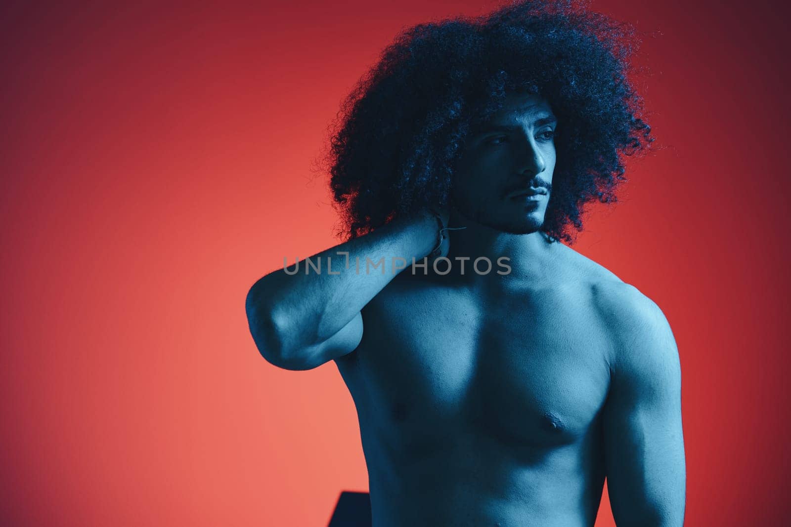 Portrait of fashion man with curly hair on red background with stylish glasses, multinational, colored light, black leather jacket trend, modern concept, sexy body. High quality photo