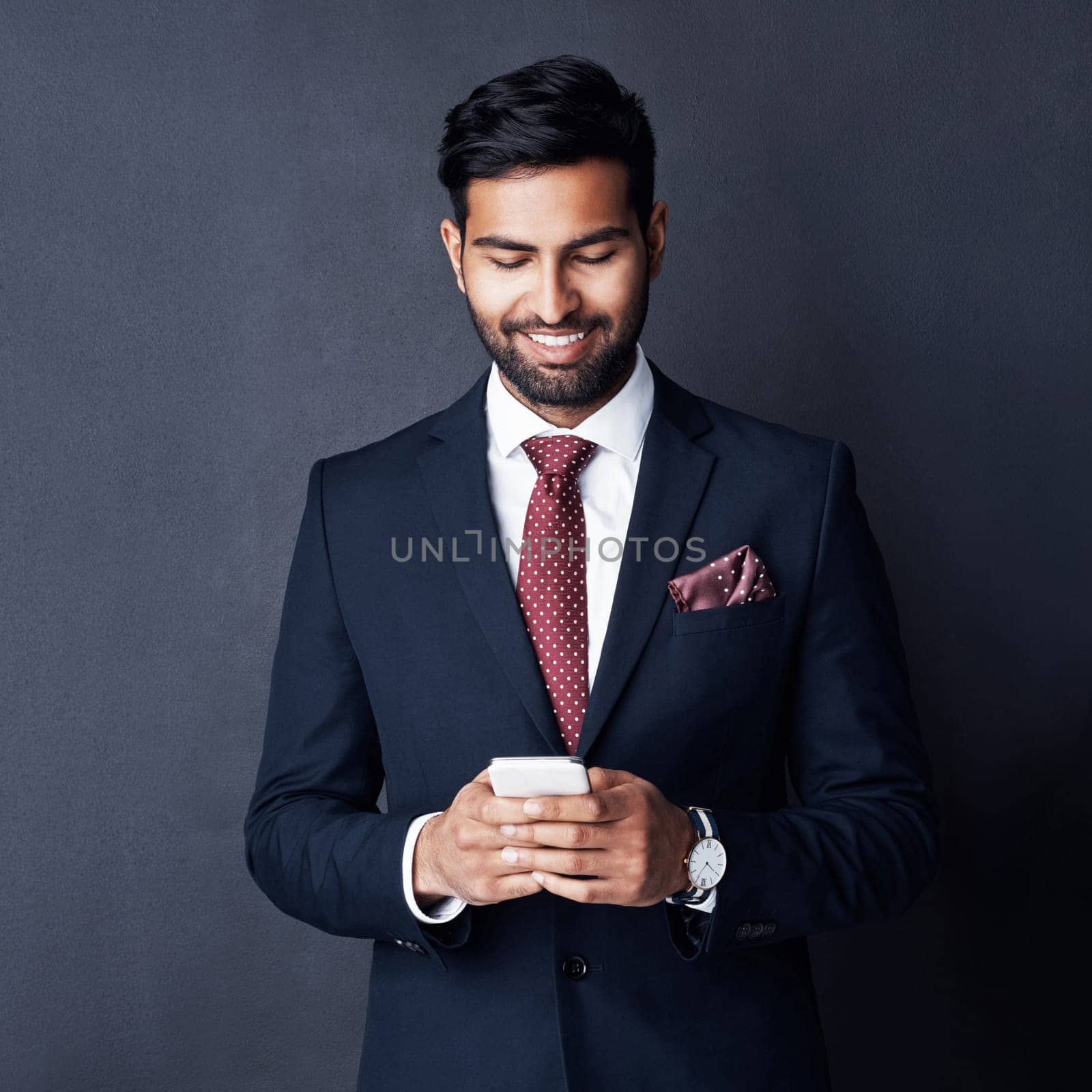 Keeping his career on track by staying connected. Studio shot of a young businessman using a mobile phone against a gray background. by YuriArcurs