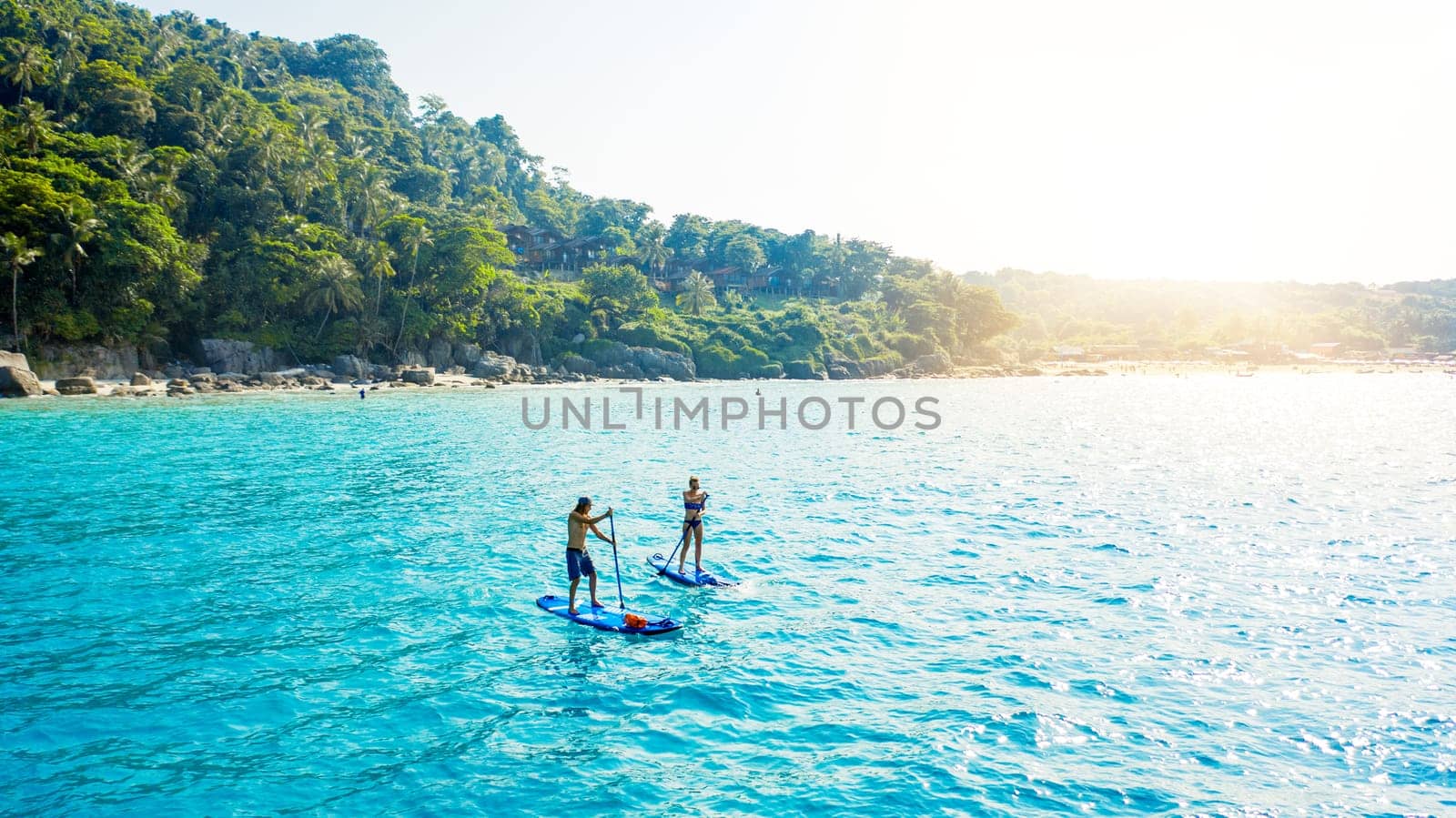 Life at sea is easy. a man and woman paddle boarding across the sea