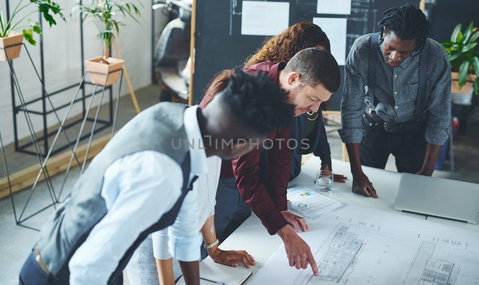 This plan will take us to the top. a team of professionals working on blueprints in an office. by YuriArcurs