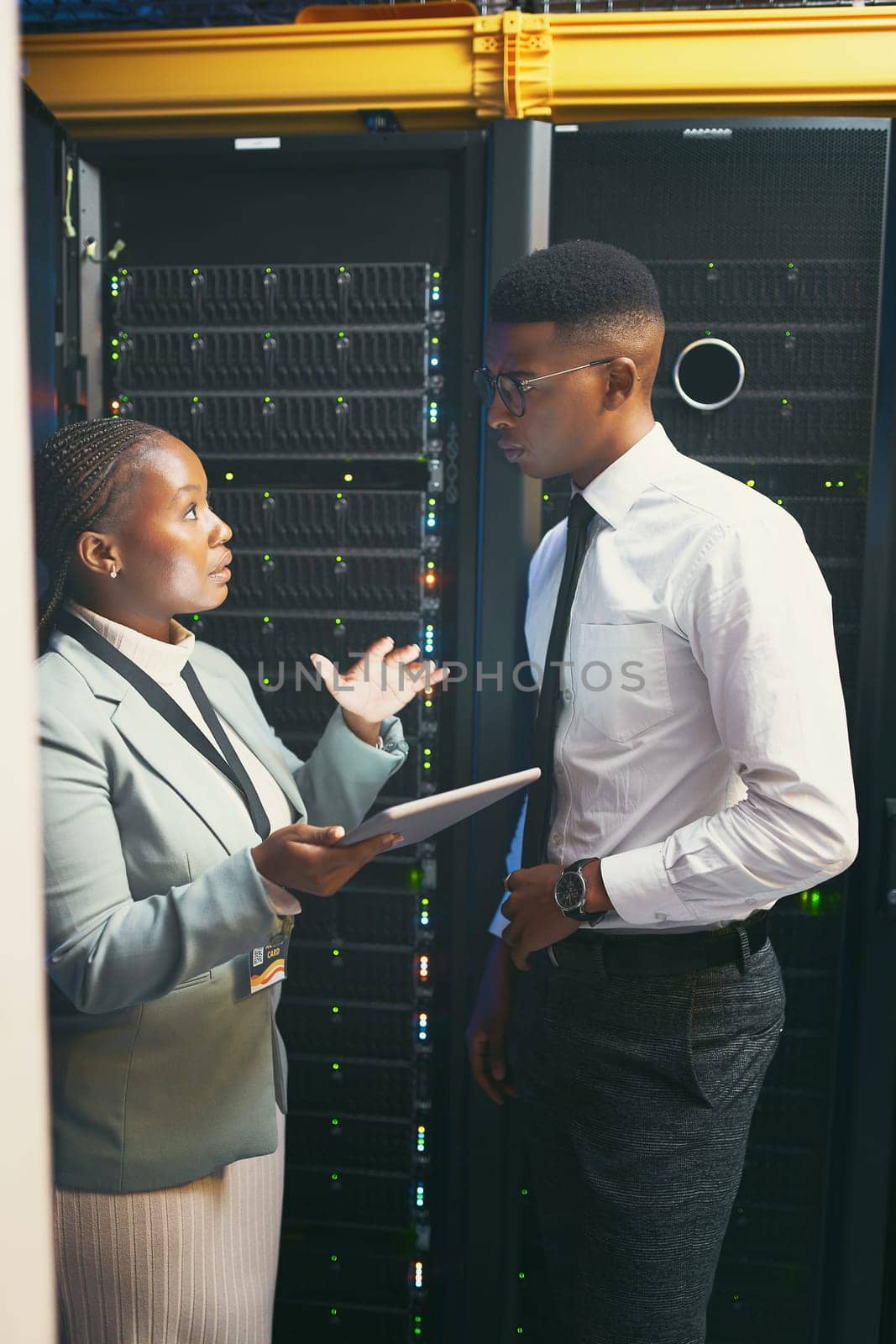 Please help me with this. two young IT specialists standing in the server room and having a discussion while using a digital tablet
