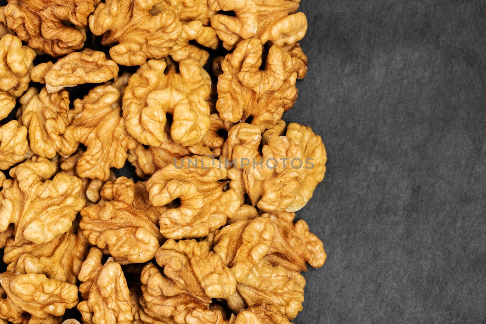 Walnuts. Walnut kernels on dark stone table. Top view, flat layout with space for copy.