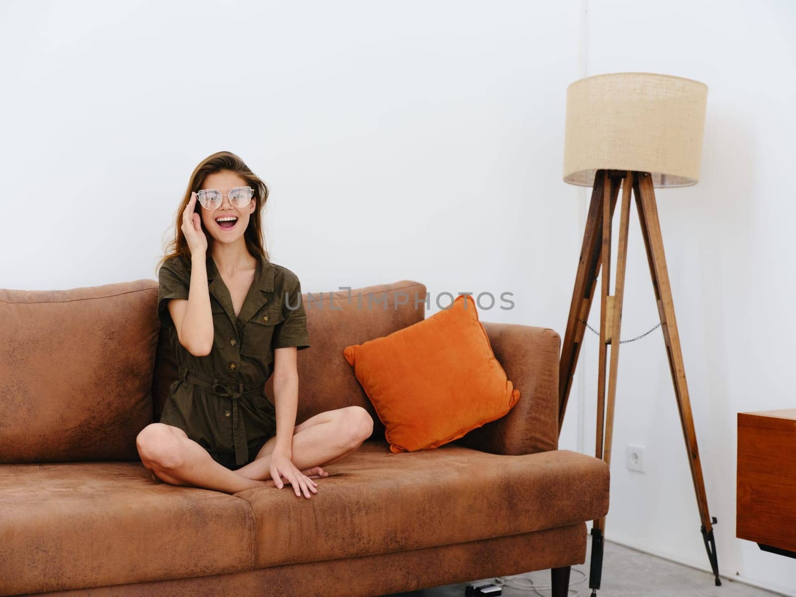Woman model sitting on the couch at home smile, surprise, joy and relaxation, modern interior lifestyle, copy space, fall color palette. by SHOTPRIME