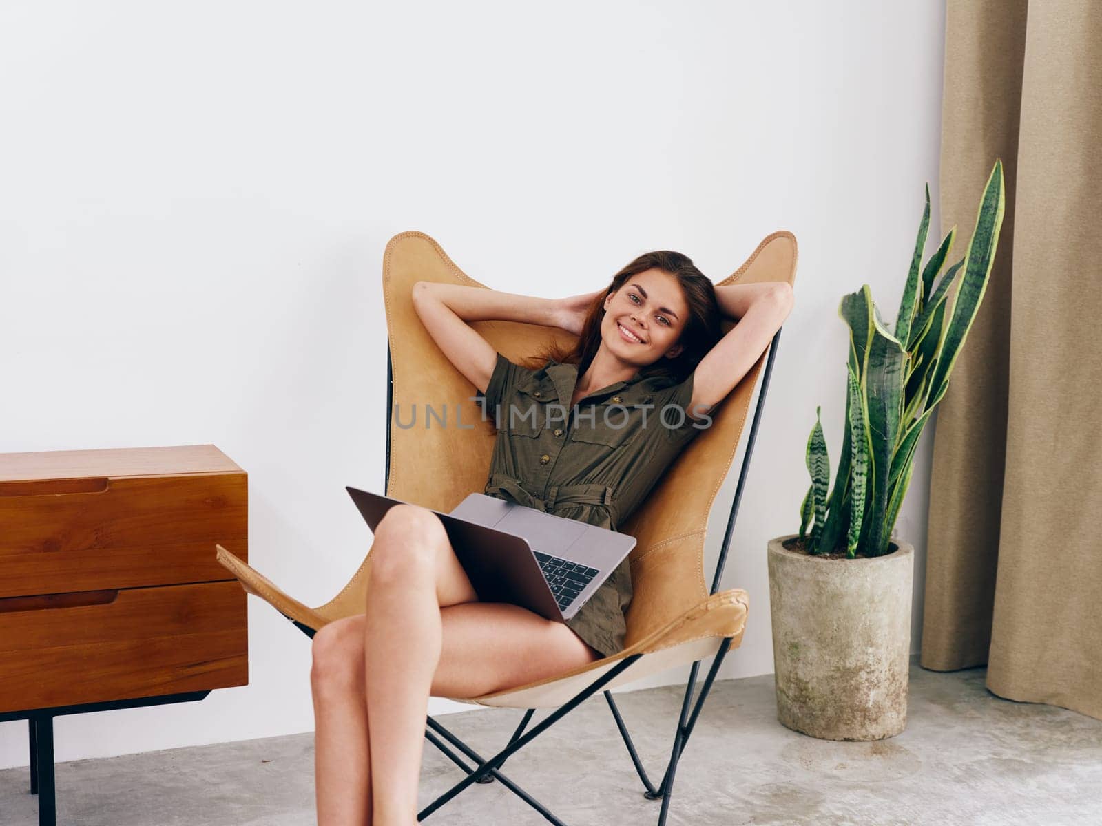 Woman freelance student sitting in a chair with a laptop work at home smile and relax, modern stylish interior Scandinavian lifestyle, copy space. by SHOTPRIME