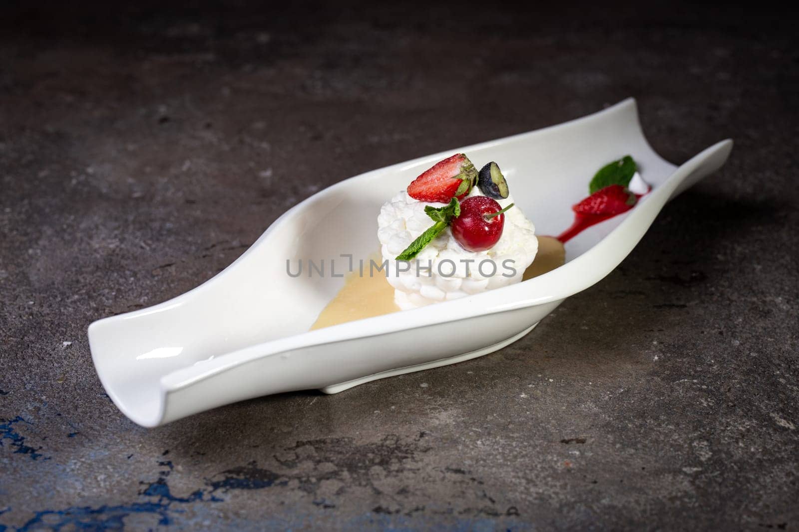 white dessert fresh meringue with strawberries on a beautiful white dish on a dark background by Pukhovskiy