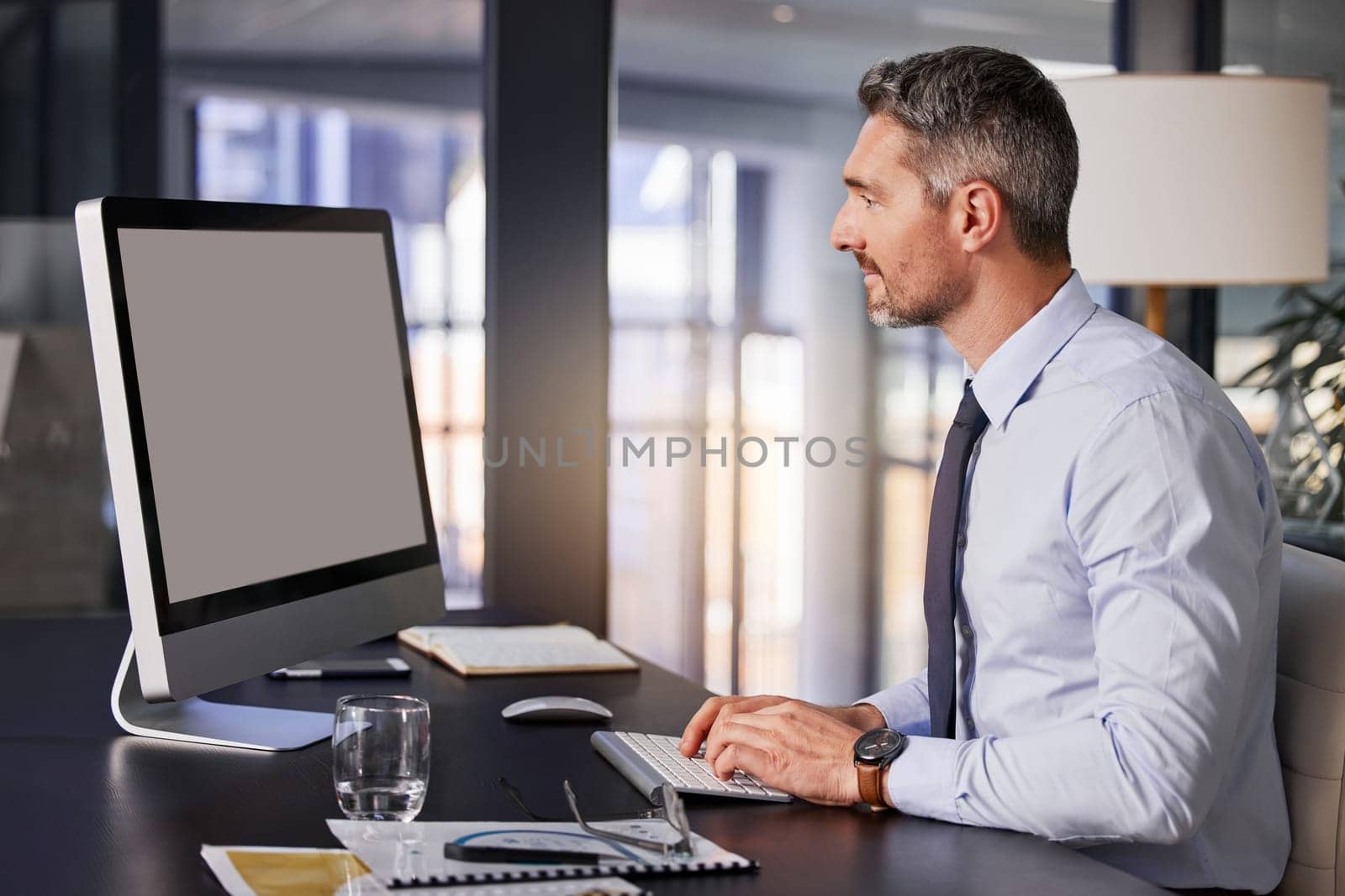 Computer, email and report with a business man typing while sitting at a desk in his office at work. Planning, research and technology with a male manager working online for finance or accounting.