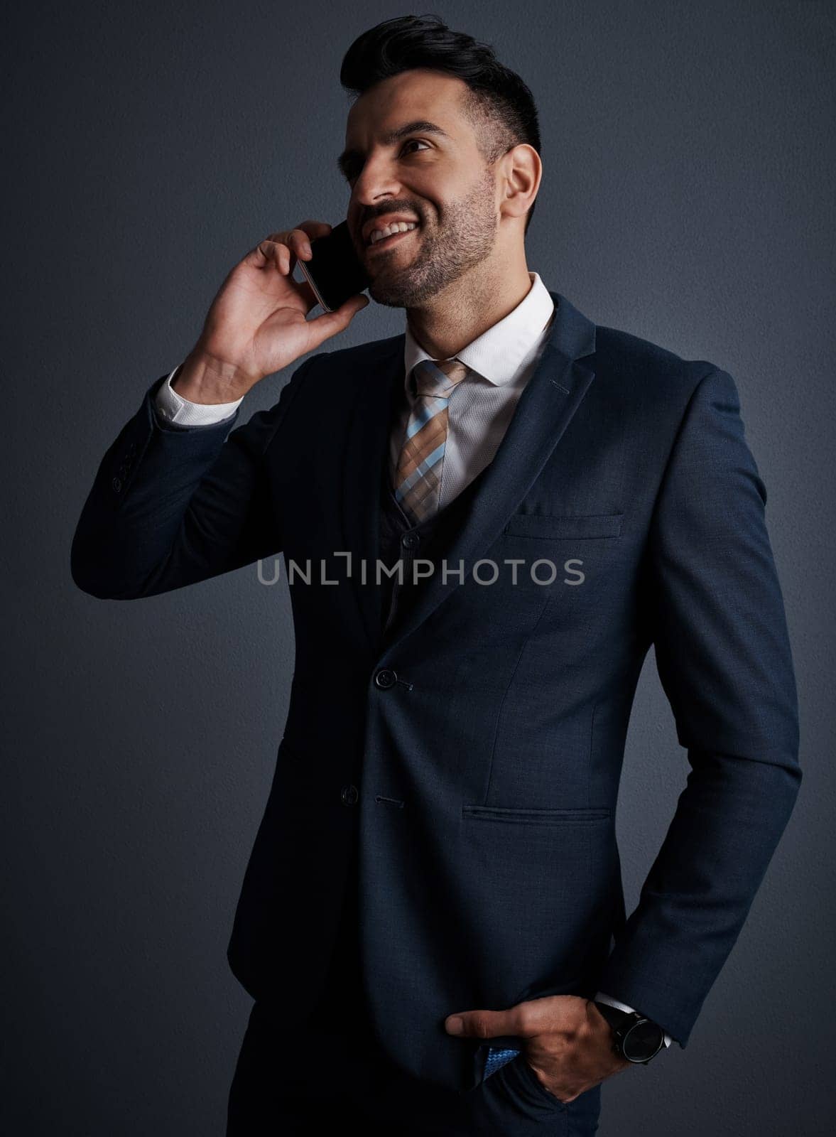 Effective communication is the key to success. Studio shot of a stylish young businessman using a mobile phone against a gray background. by YuriArcurs