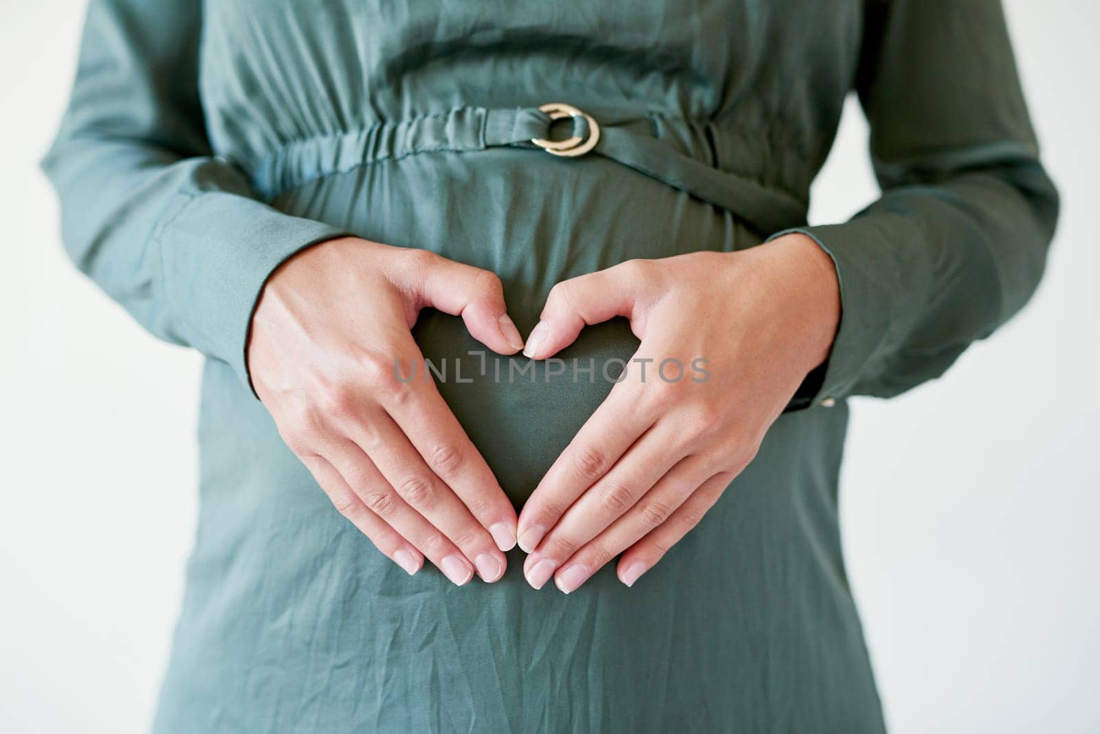 This is a love like no other. a mother to be forming a heart shape over her pregnant belly