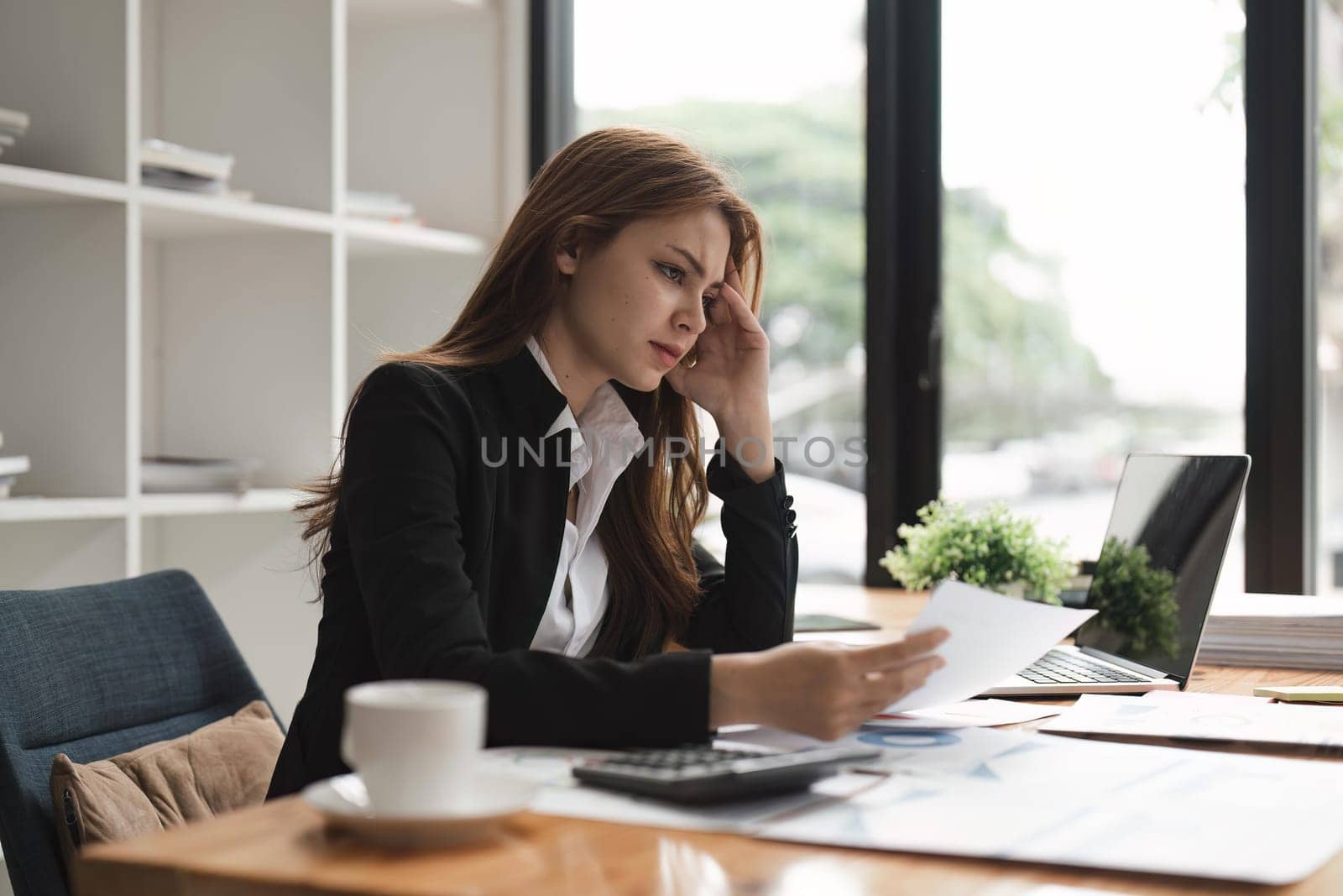 Tired business woman in stress works at a laptop. migraine attack.