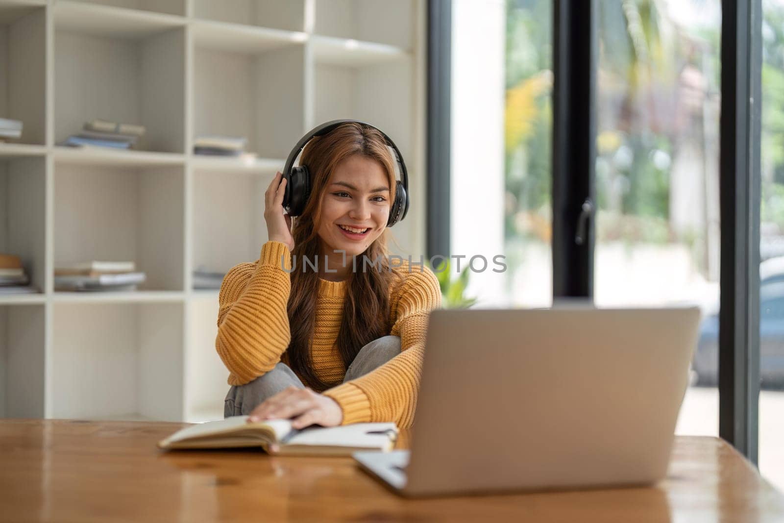 Young woman having video call on her computer at home. Smiling girl studying online with teacher.