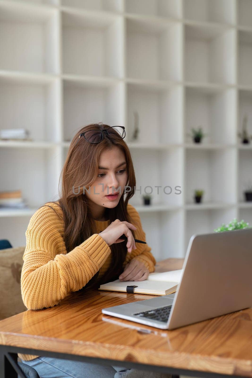 Young woman having video call on her computer at home. Smiling girl studying online with teacher.