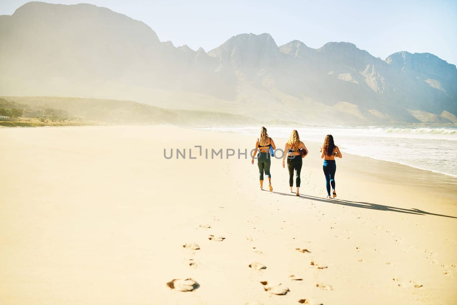 Lets head over to our yoga spot. Rearview shot of three young woman looking for a spot on the beach to practice yoga