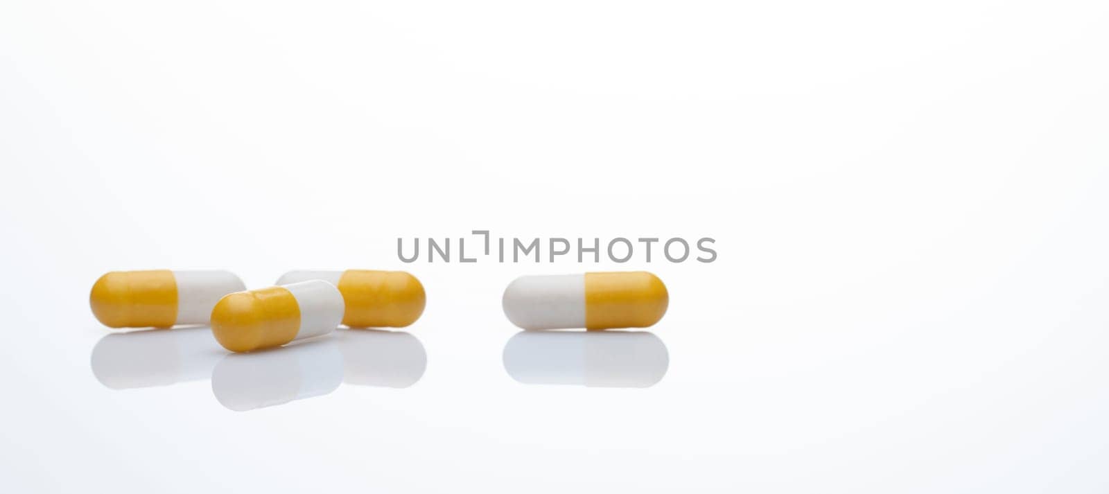 Yellow and white capsule pills on white background. Prescription drugs. Pharmaceutical industry. Health and medical care concept. Online pharmacy web banner. Pharmacology for doctors and pharmacists.