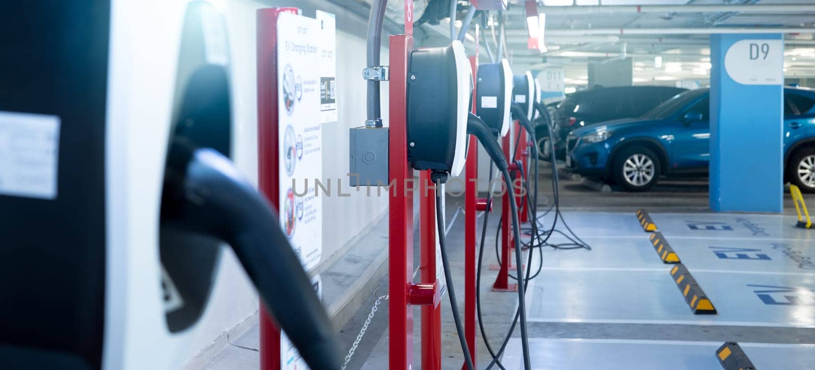 Electric car charging station for charge EV battery. Plug for electric vehicle. EV charger. Charging point at car parking lot of the mall. Clean and sustainable energy. Commercial EV charging point.