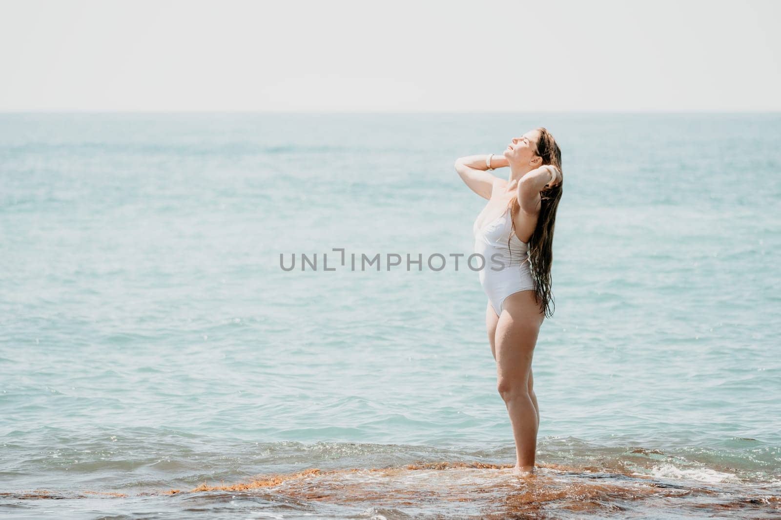 Woman sea yoga. Back view of free calm happy satisfied woman with long hair standing on top rock with yoga position against of sky by the sea. Healthy lifestyle outdoors in nature, fitness concept.