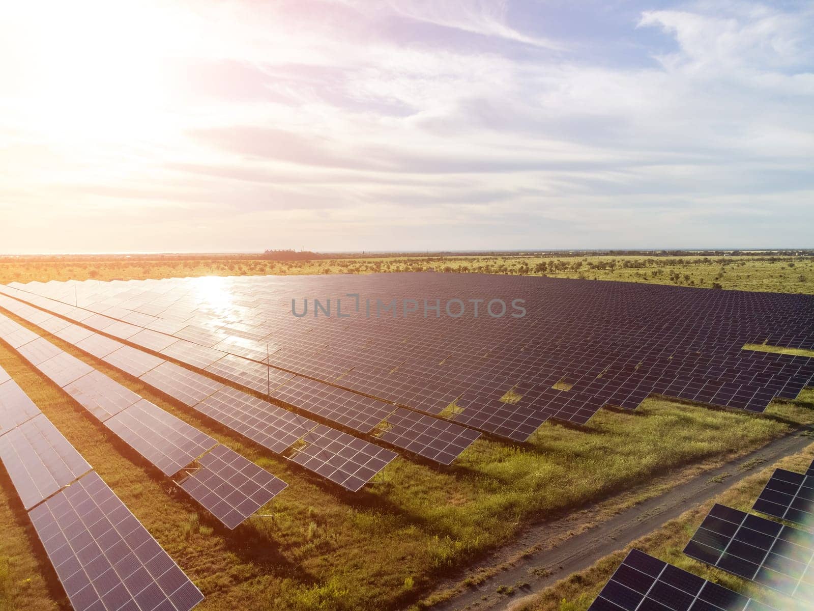 Aerial top view of a solar panels power plant. Photovoltaic solar panels at sunrise and sunset in countryside from above. Modern technology, climate care, earth saving, renewable energy concept