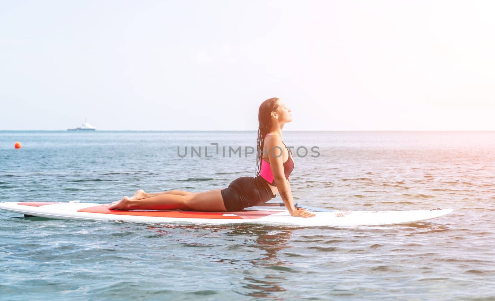 Woman sup yoga. Happy young sporty woman practising yoga pilates on paddle sup surfboard. Female stretching doing workout on sea water. Modern individual female outdoor summer sport activity