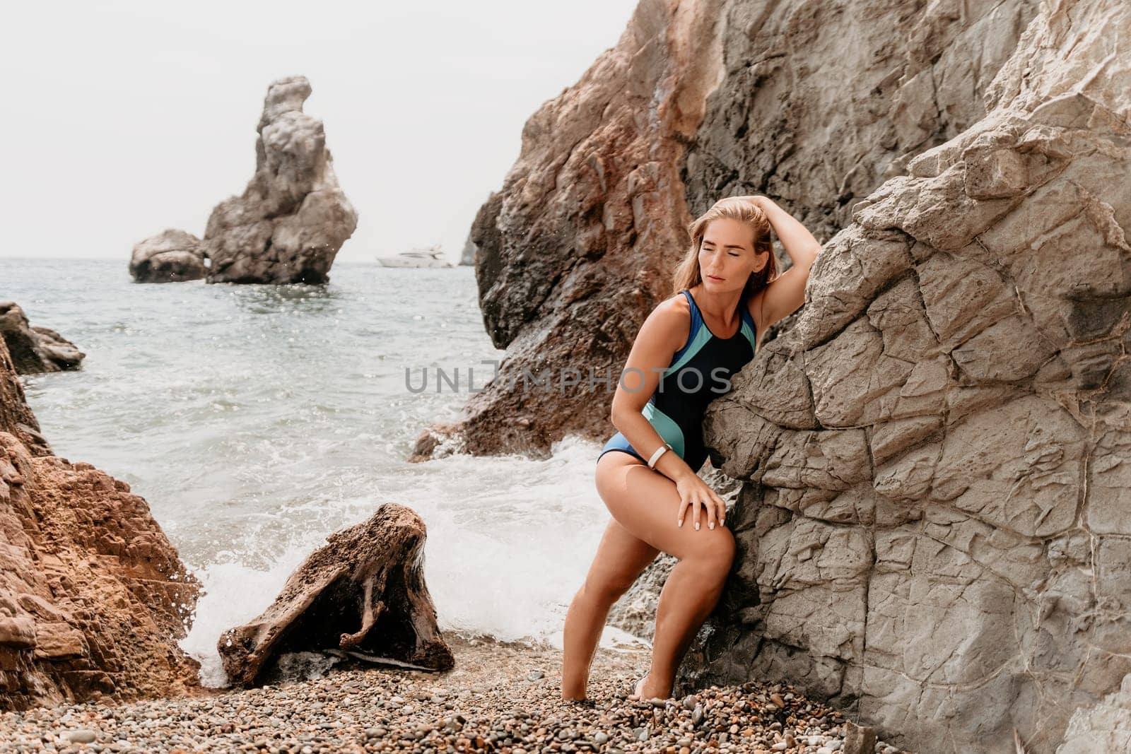 Woman travel sea. Young Happy woman in a long red dress posing on a beach near the sea on background of volcanic rocks, like in Iceland, sharing travel adventure journey