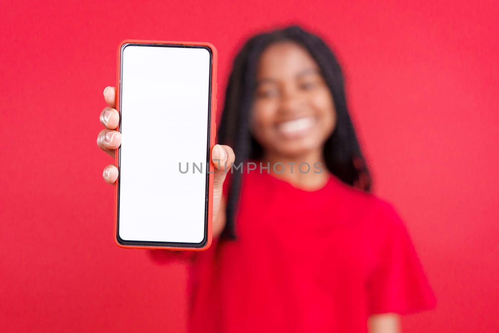 Blank screen of the mobile in hands of african woman in studio with red background