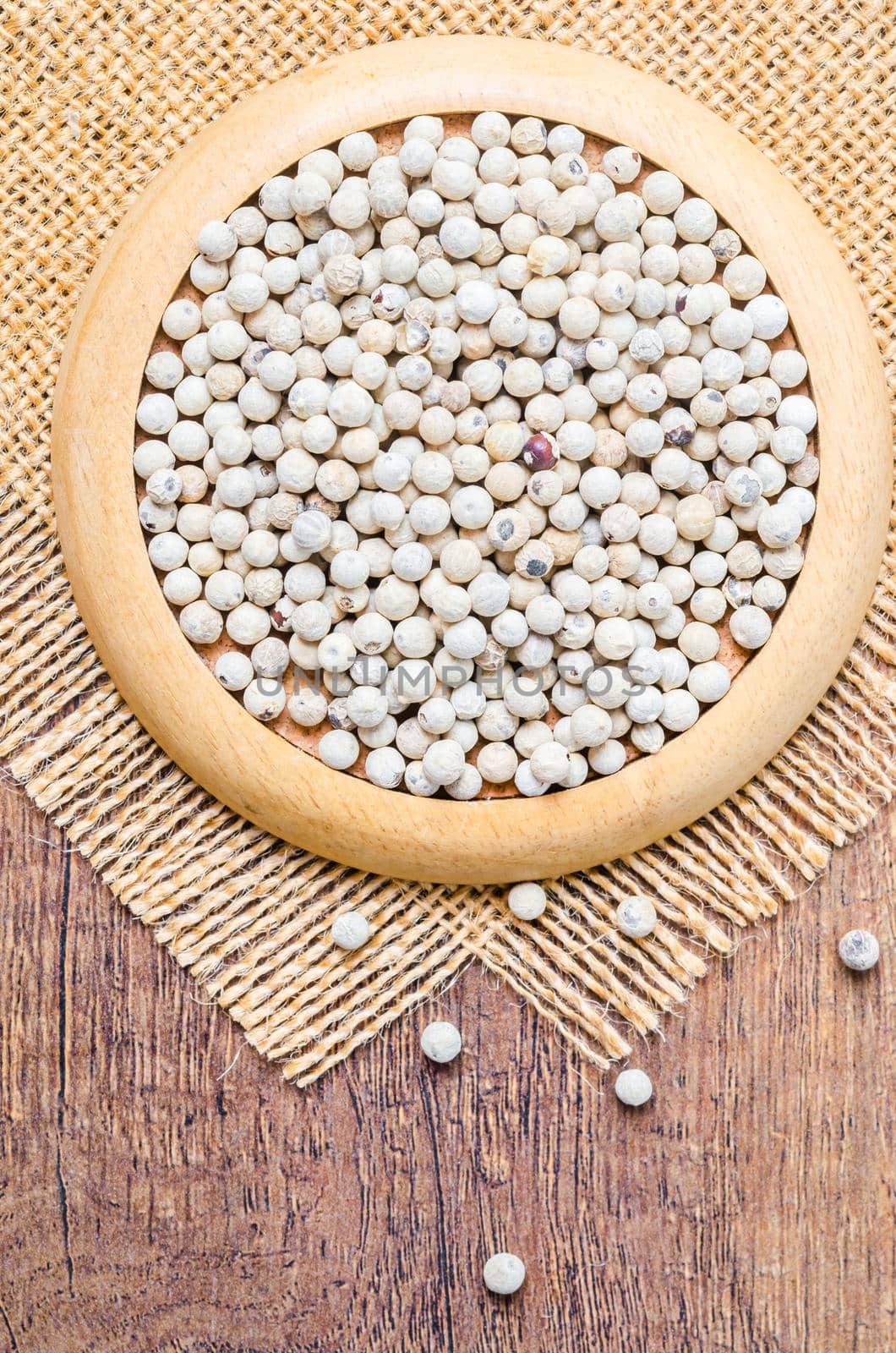 Dried white peppercorn seeds in wooden plate.