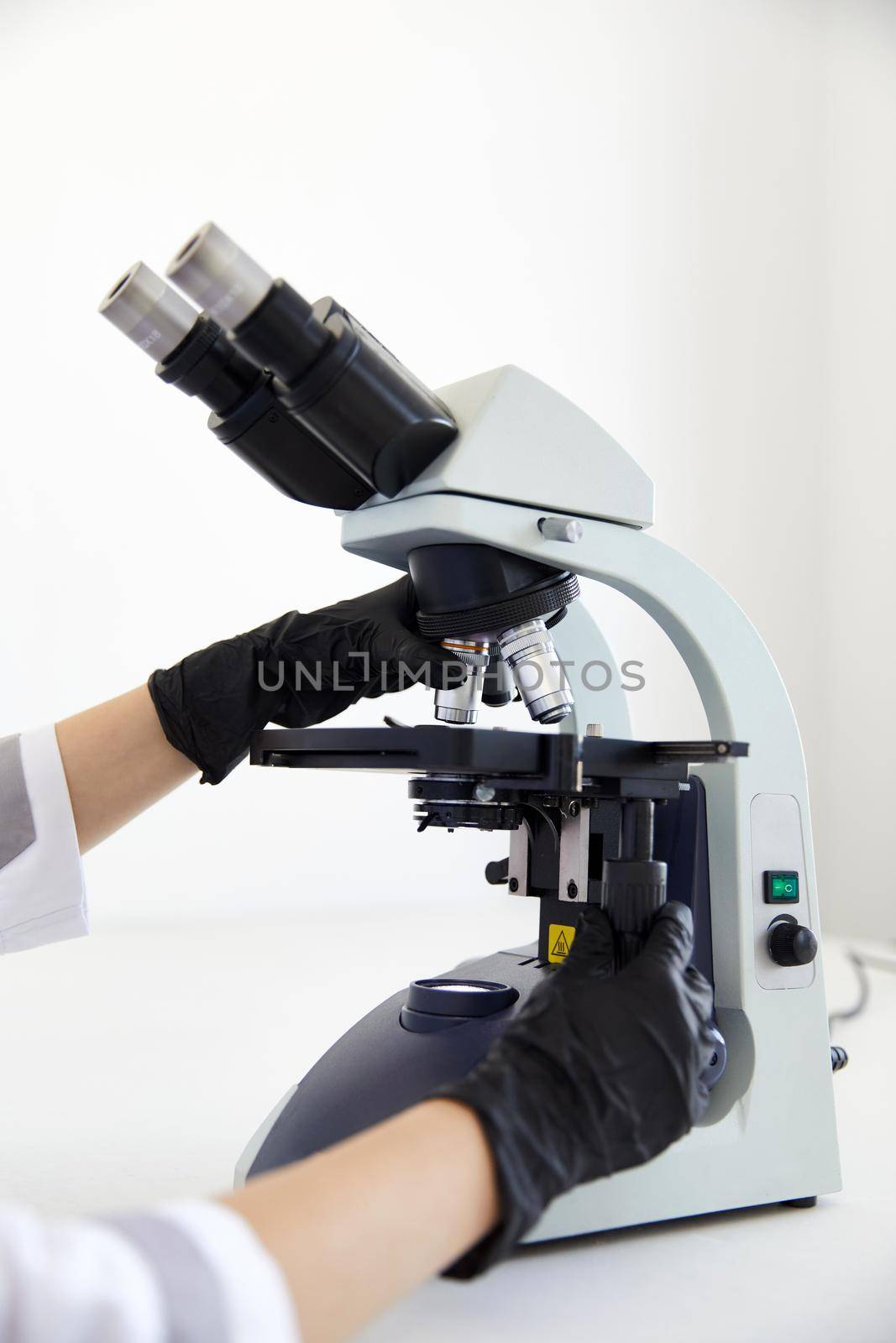 Closeup of microscope and hands wearing rubber gloves in modern laboratory . High quality photo