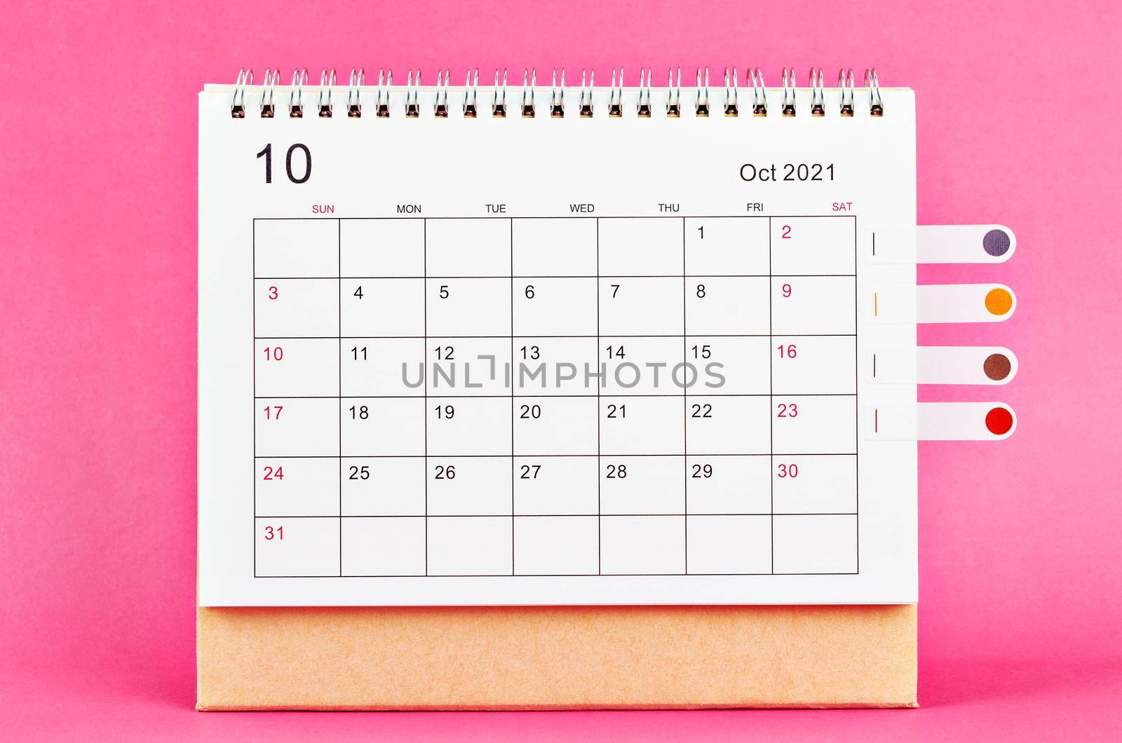 The October 2021 desk calendar on pink background.