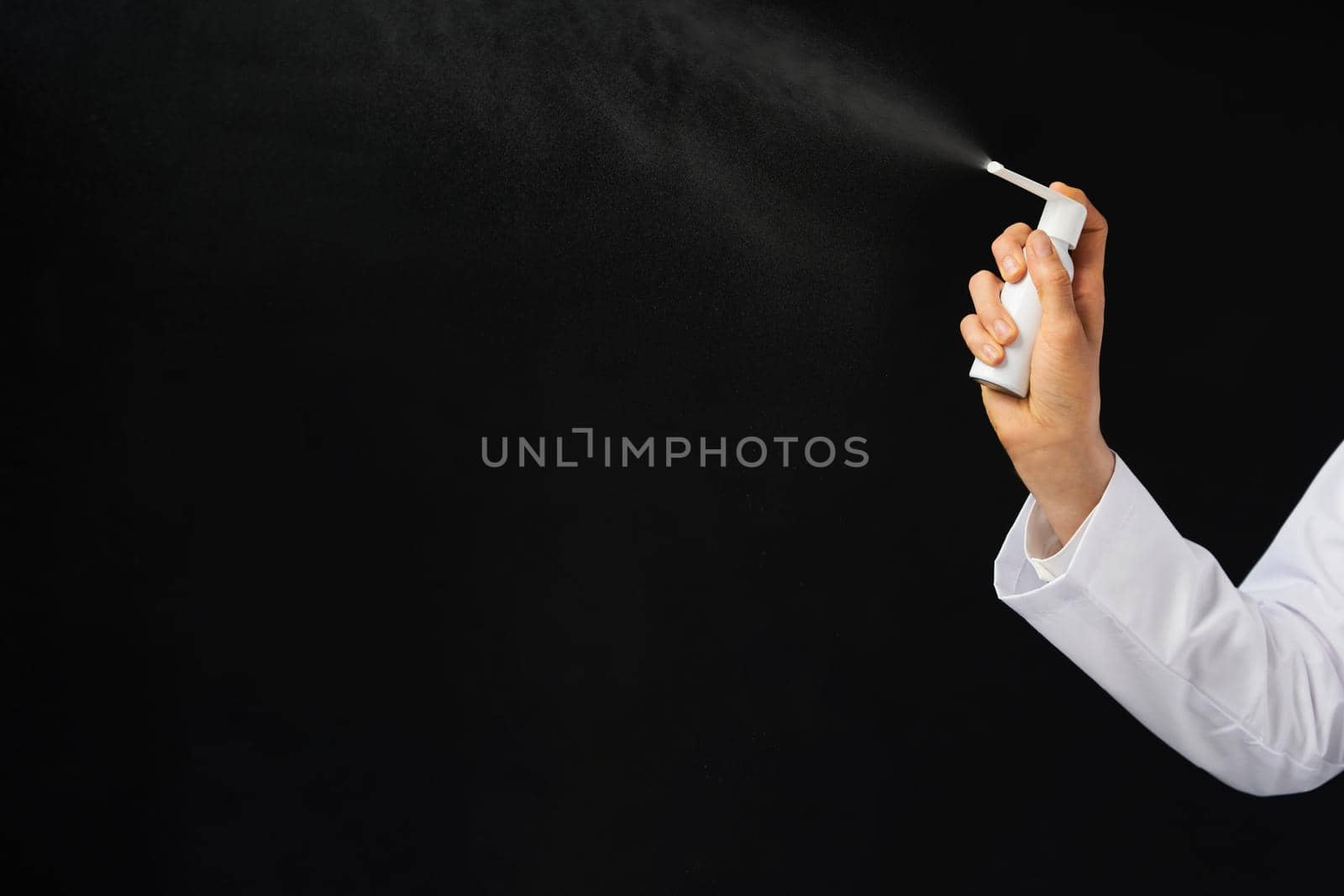Cropped view of female hand using spray over a black background