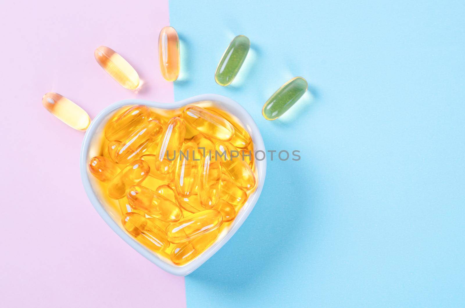 Heart-shape plate with fish oil capsules on beautiful background