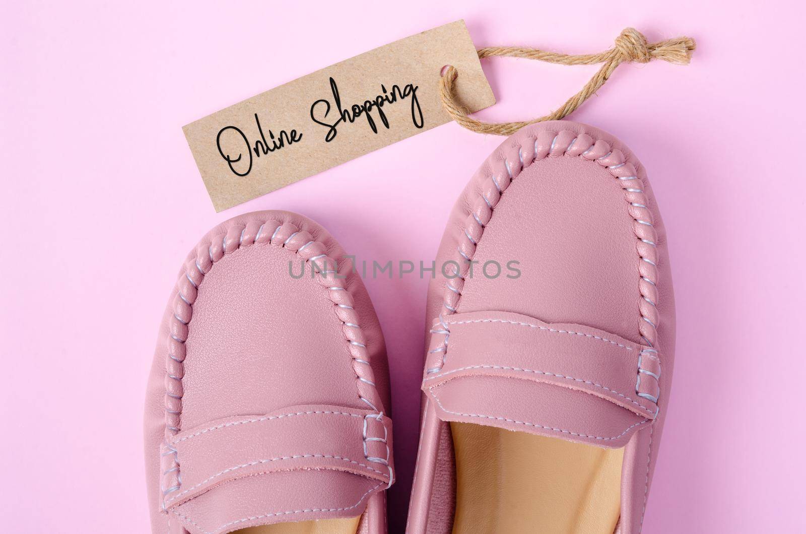 Beautiful pink women shoes with Onlin Shopping tag on pink background. Business concepts.