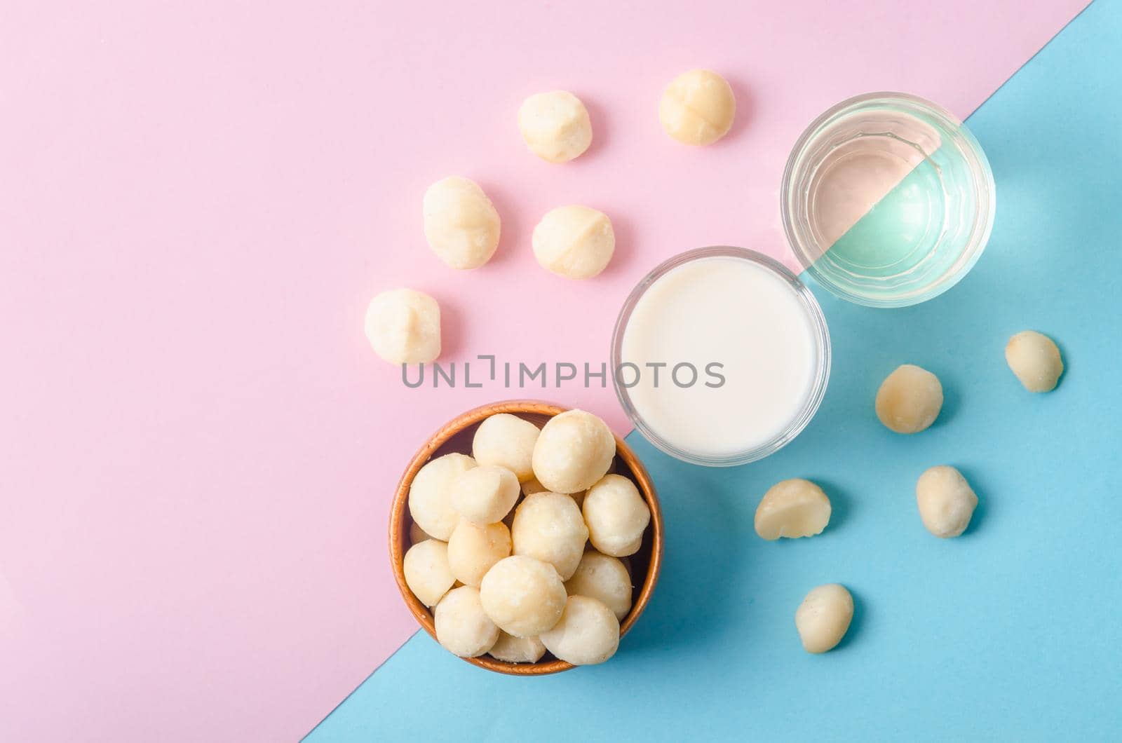 Macadamia milk in a glass and a bowl of macadamia nuts with oil on a beautiful background.