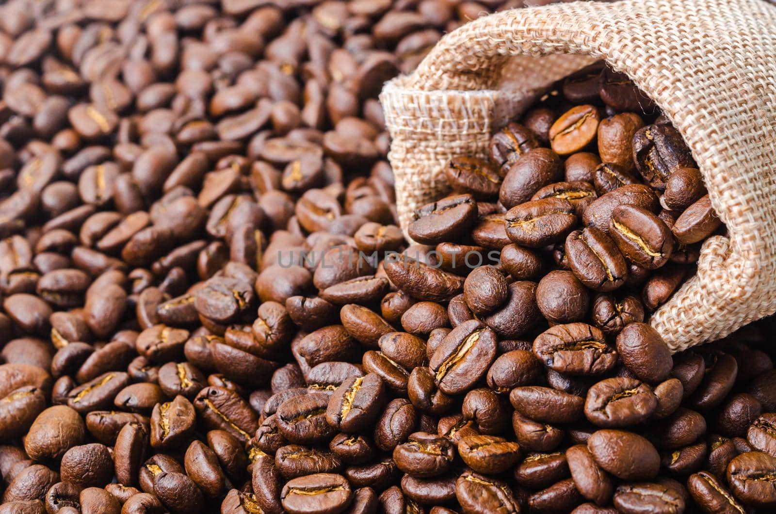 Top view of coffee beans in sack bag on coffee beans background.