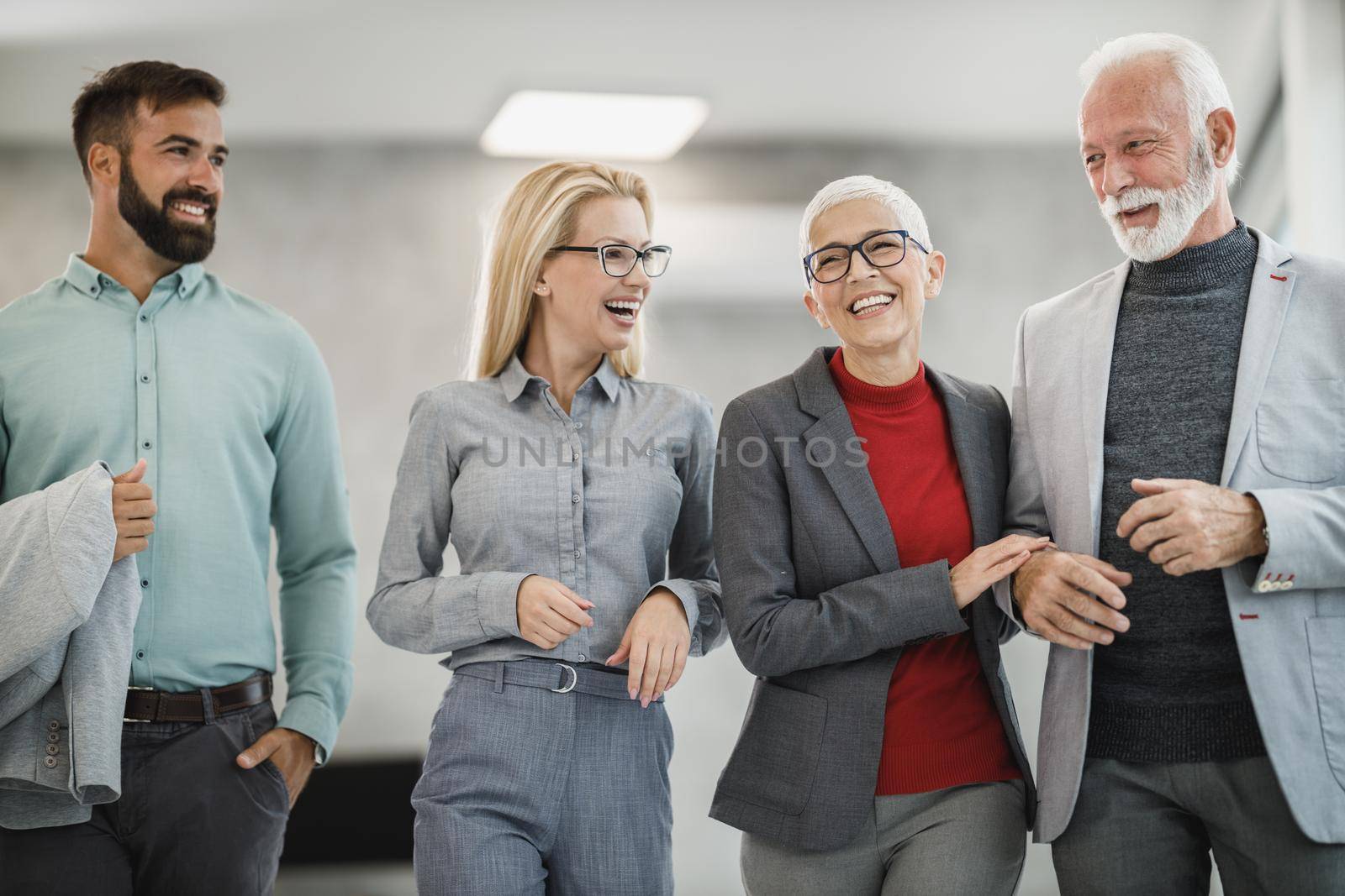 A group of cheerful business people walking and talking in a modern office.