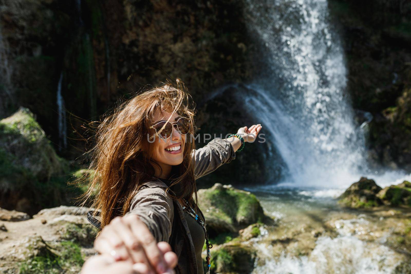 A cheerful young couple enjoying the view of the beautiful waterfall.