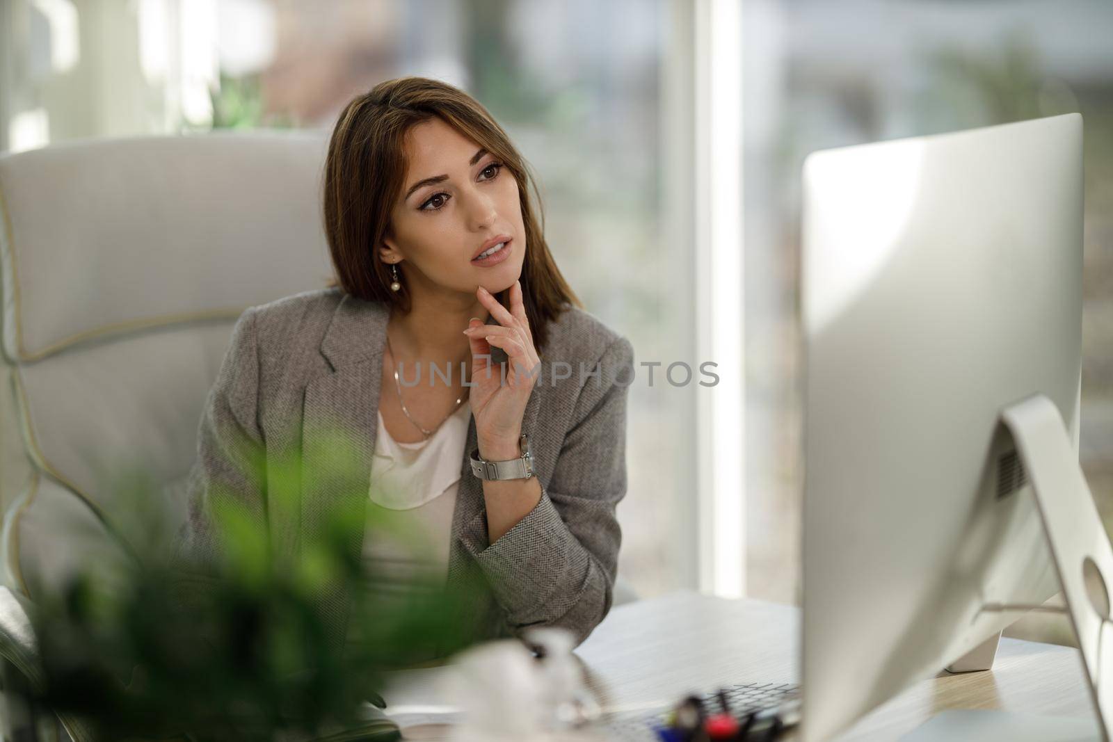 An attractive business woman sitting alone in her home office and working on computer.
