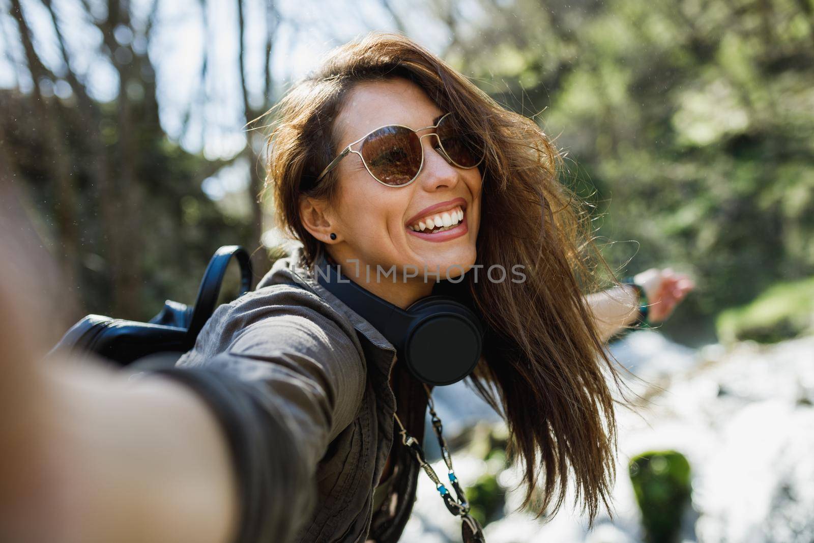 A smiling young woman making selfie while enjoying the view of nature.