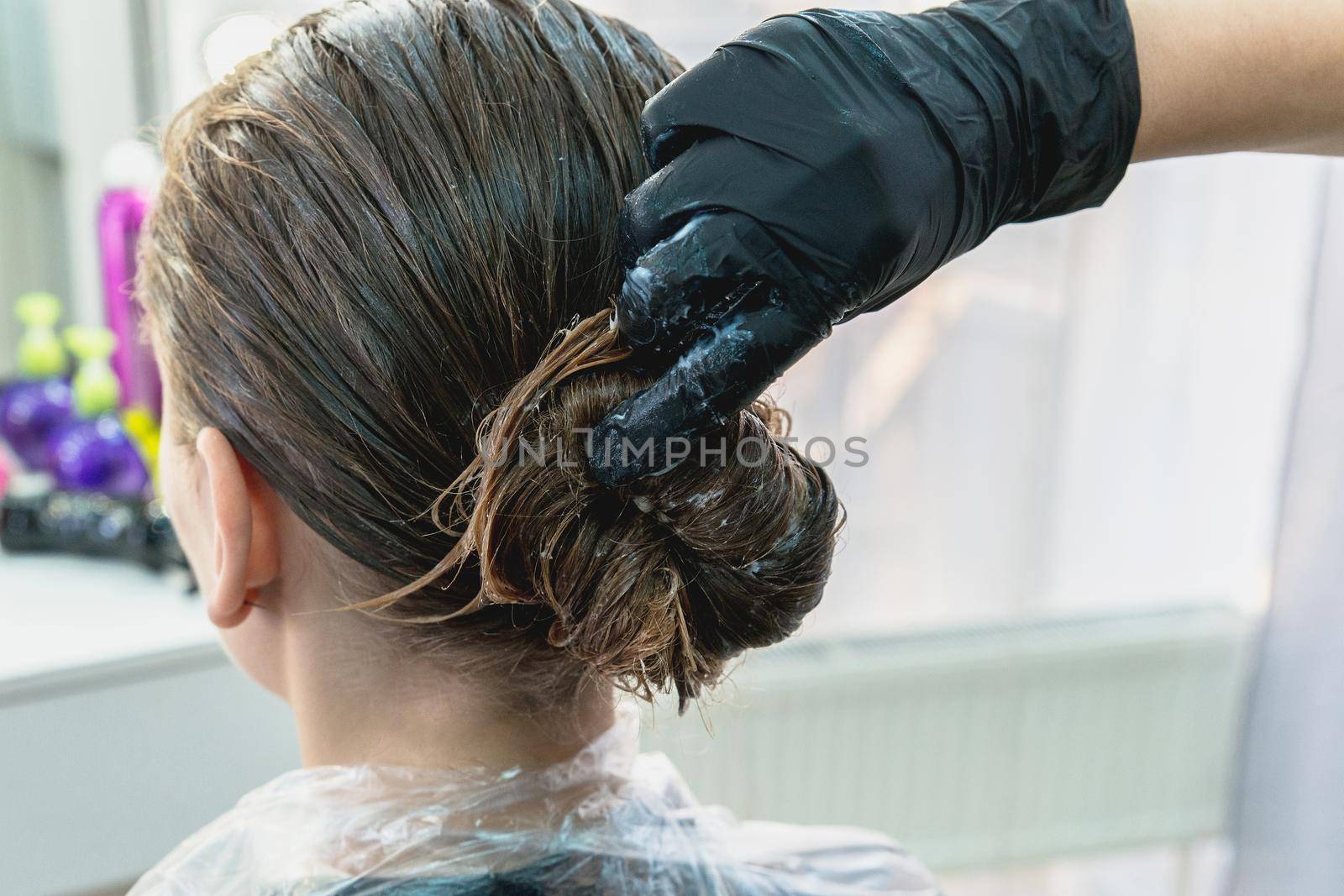 Young girl having hair treatment mask in a beauty salon, young girl during care process by Mariakray