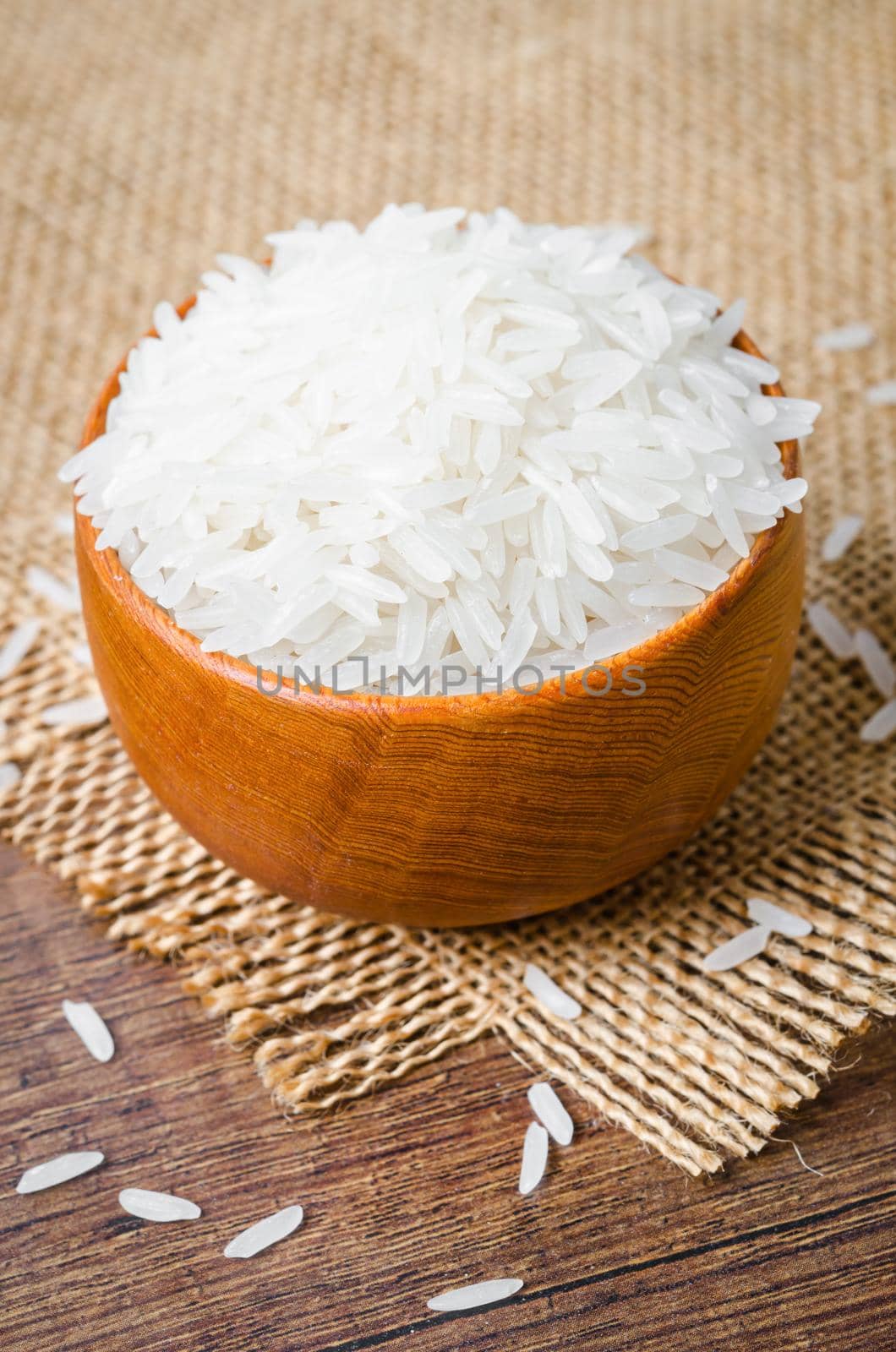 Organic Thai Jasmine rice grain in wooden bowl. by Gamjai