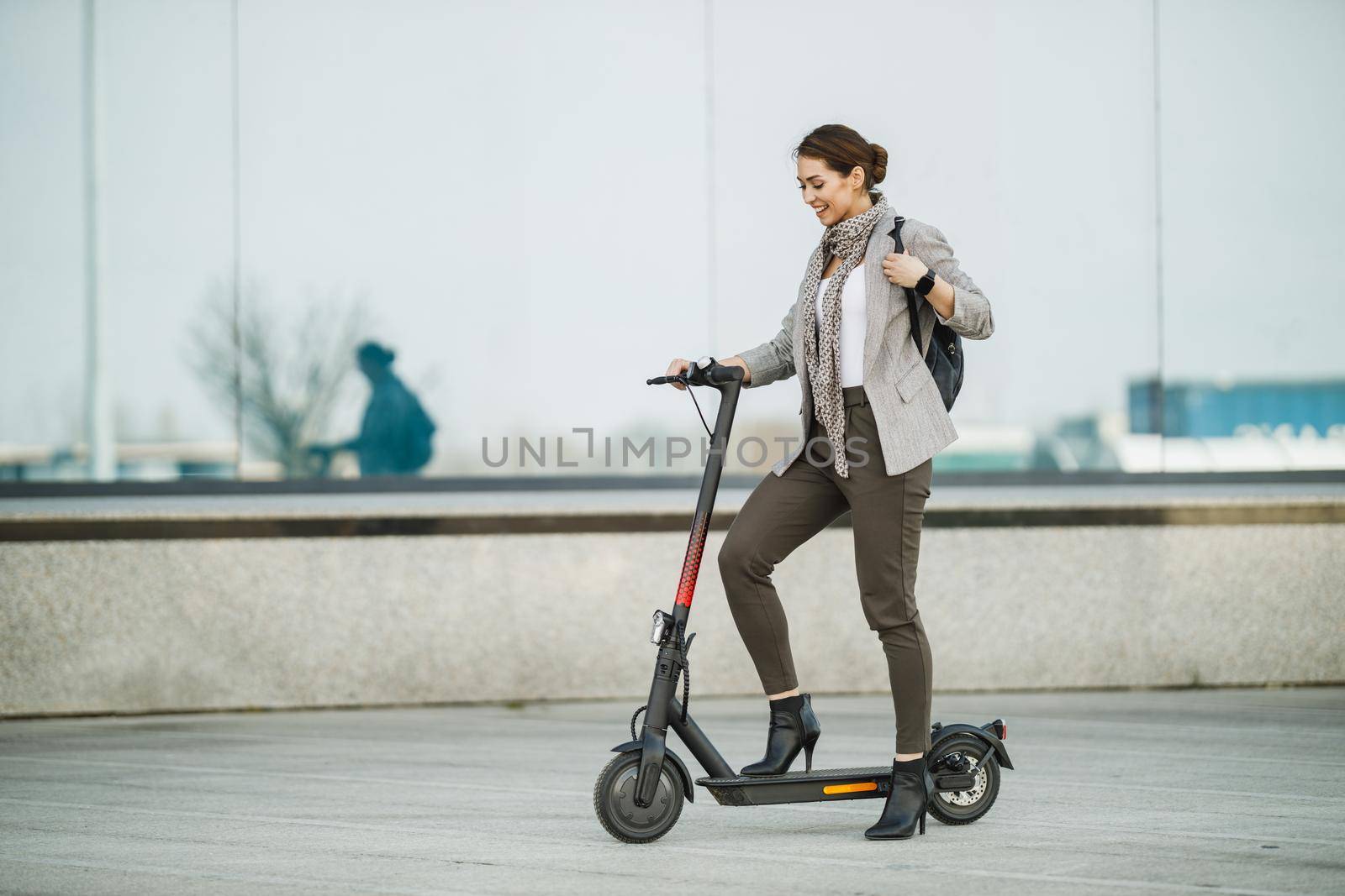 A young businesswoman riding an electric scooter on her way to work.