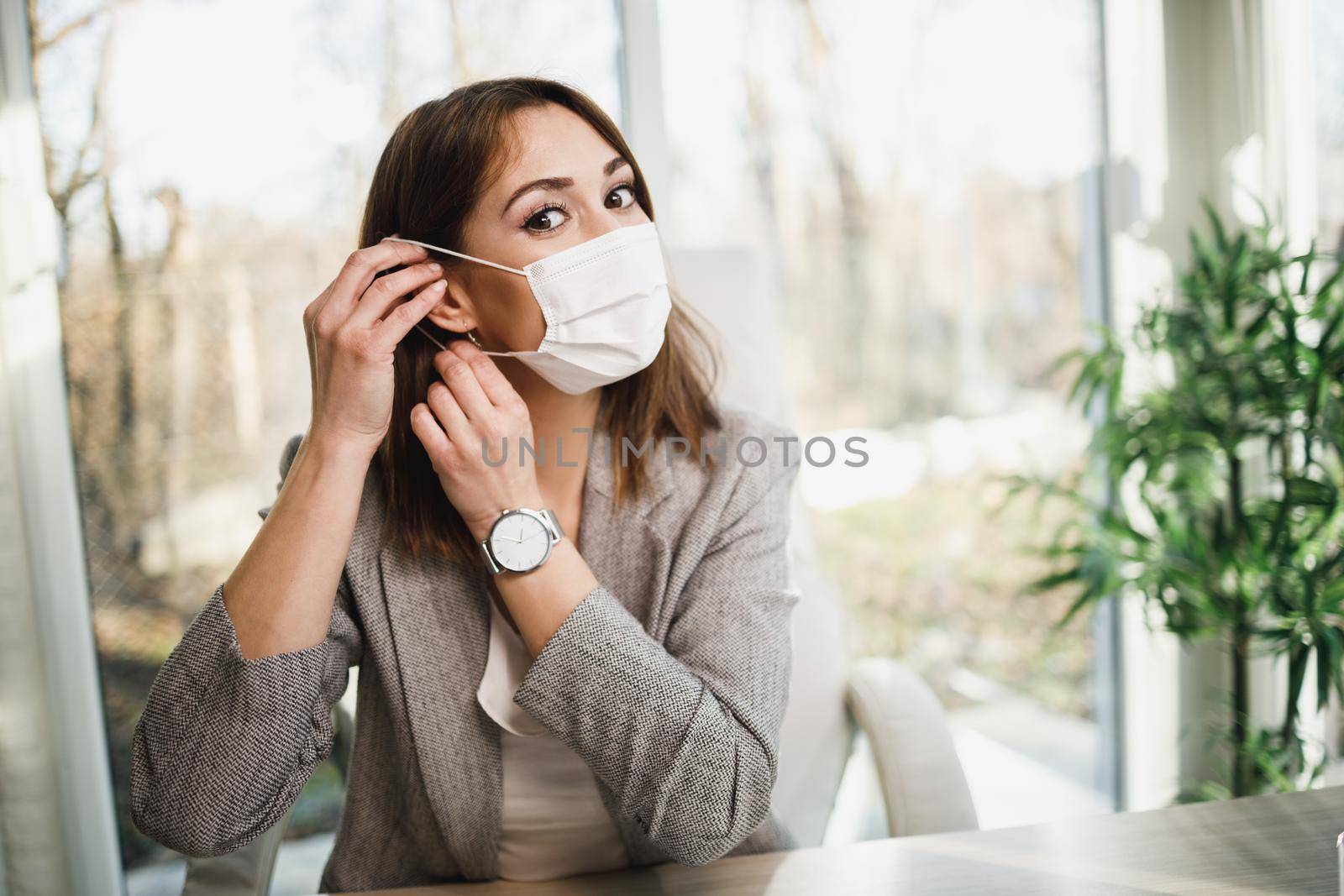 An attractive-smiling business woman with surgical mask working in her office.