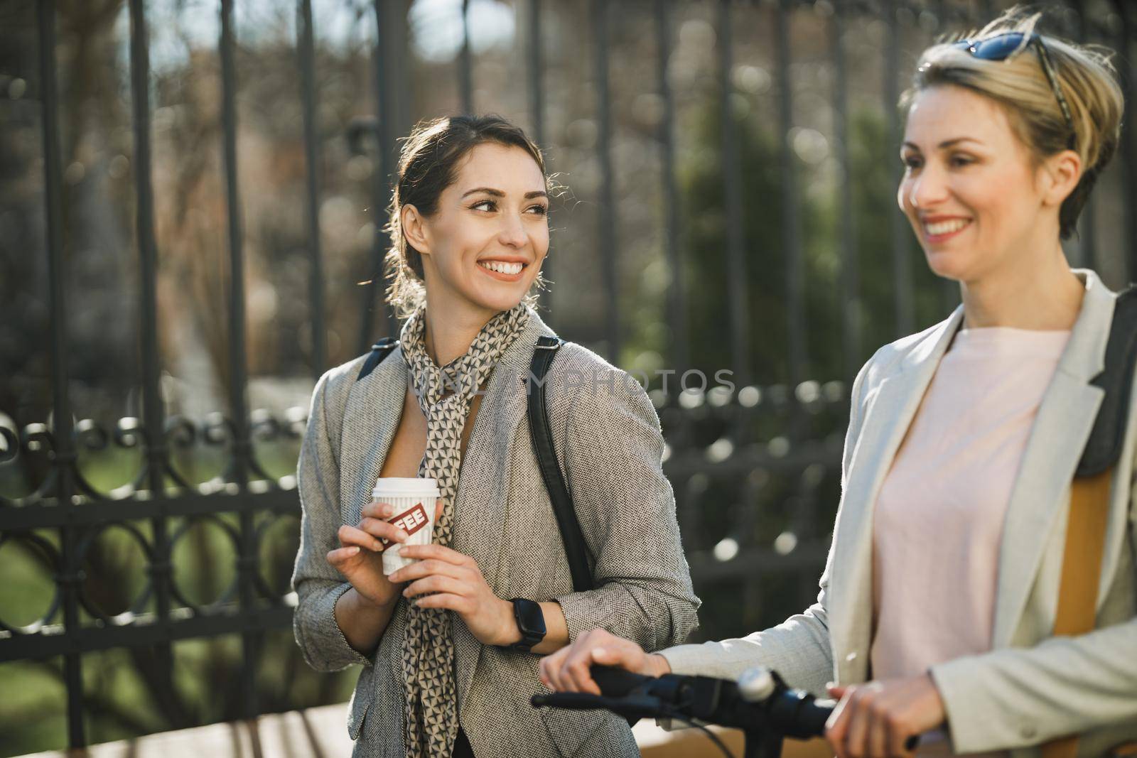 A young successful businesswoman having a coffee break and chatting while walking with her colleague.